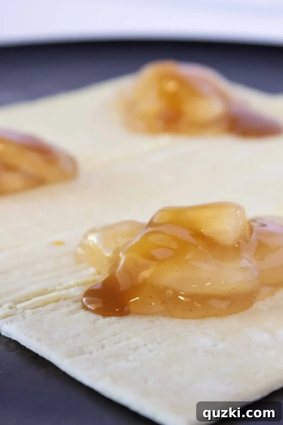 Sweet & Simple Caramel Apple Turnovers 5 A delicate drizzle of rich caramel sauce being added over the apple pie filling on a puff pastry square, enhancing the flavor.