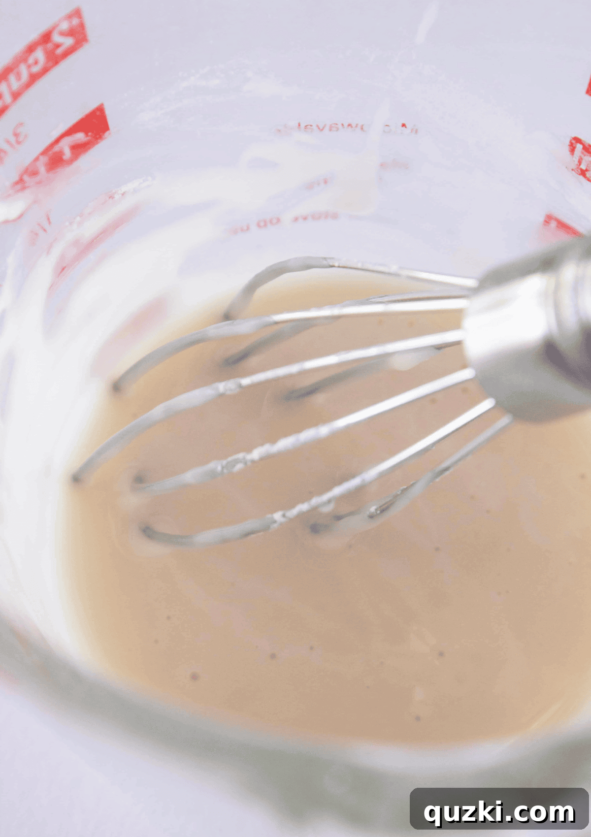 Sweet & Simple Caramel Apple Turnovers 8 Whisking together the smooth and glossy ingredients for the apple cider glaze in a white bowl, ready to top the baked turnovers.