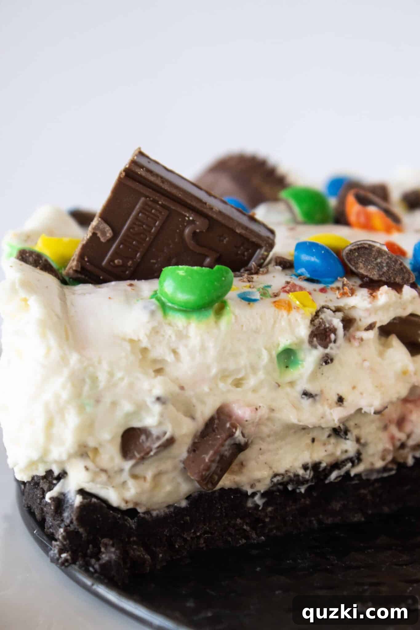 Frightfully Delicious No-Bake Candy Cheesecake 2 No Bake Halloween Candy Cheesecake that has been sliced, revealing a creamy, candy-studded interior atop a dark Oreo crust.