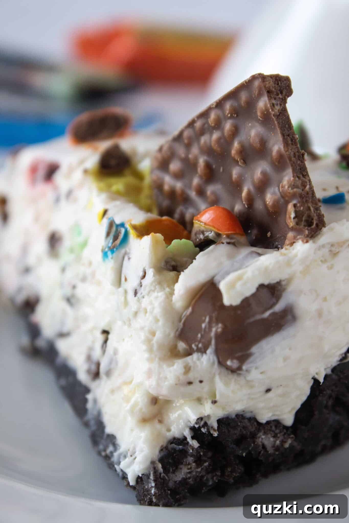 Frightfully Delicious No-Bake Candy Cheesecake 13 A close-up of a single slice of Halloween candy cheesecake, showcasing the varied candy pieces embedded in the creamy filling.