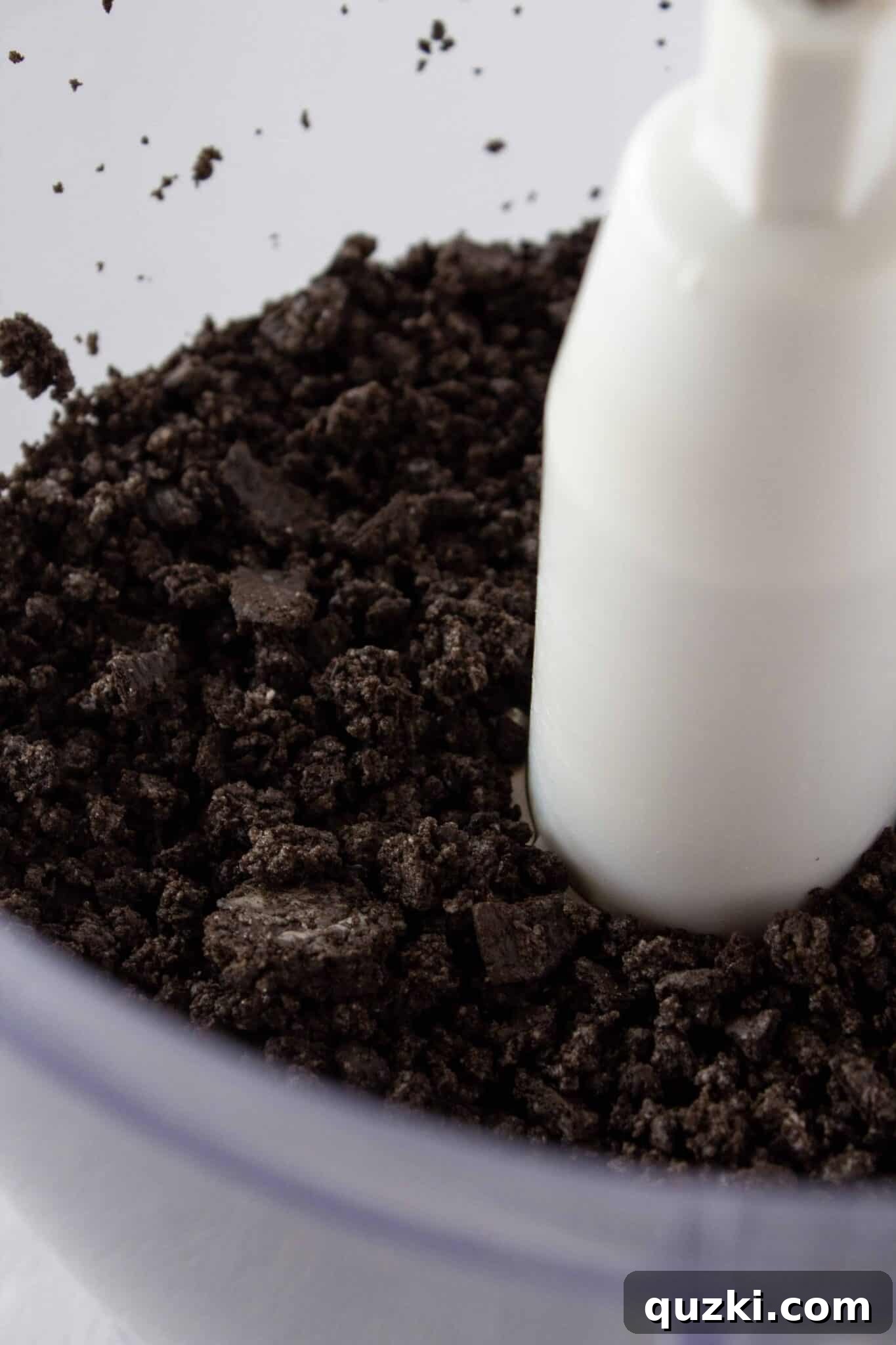 Frightfully Delicious No-Bake Candy Cheesecake 5 Close-up shot of Oreo cookies being processed into crumbs in a food processor, illustrating the initial stage of crust preparation.
