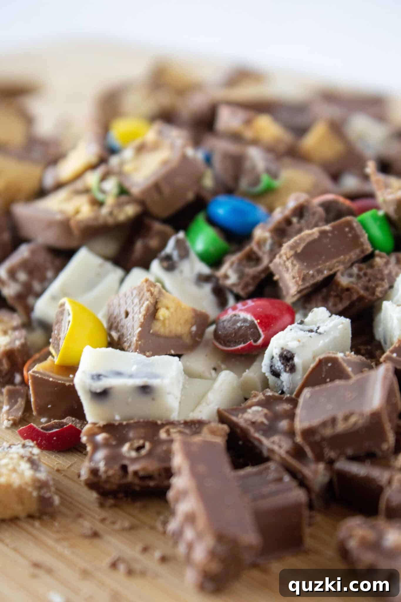 Frightfully Delicious No-Bake Candy Cheesecake 9 Hands gently folding chopped Halloween candy into the creamy cheesecake filling.