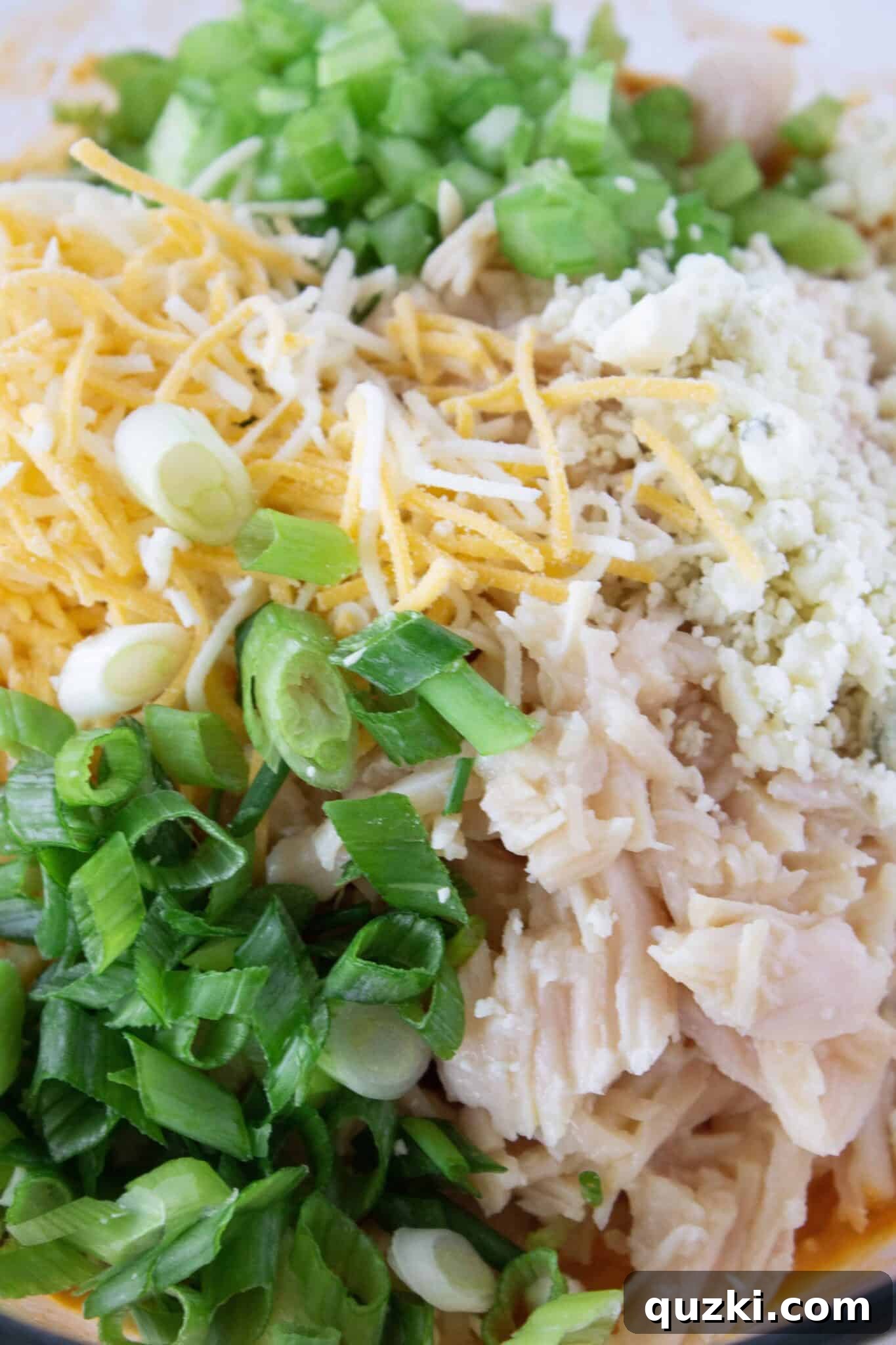 The Ultimate Buffalo Chicken Wrap Recipe 4 Finishing the buffalo chicken wrap filling by adding shredded cheese, green onion, and celery.