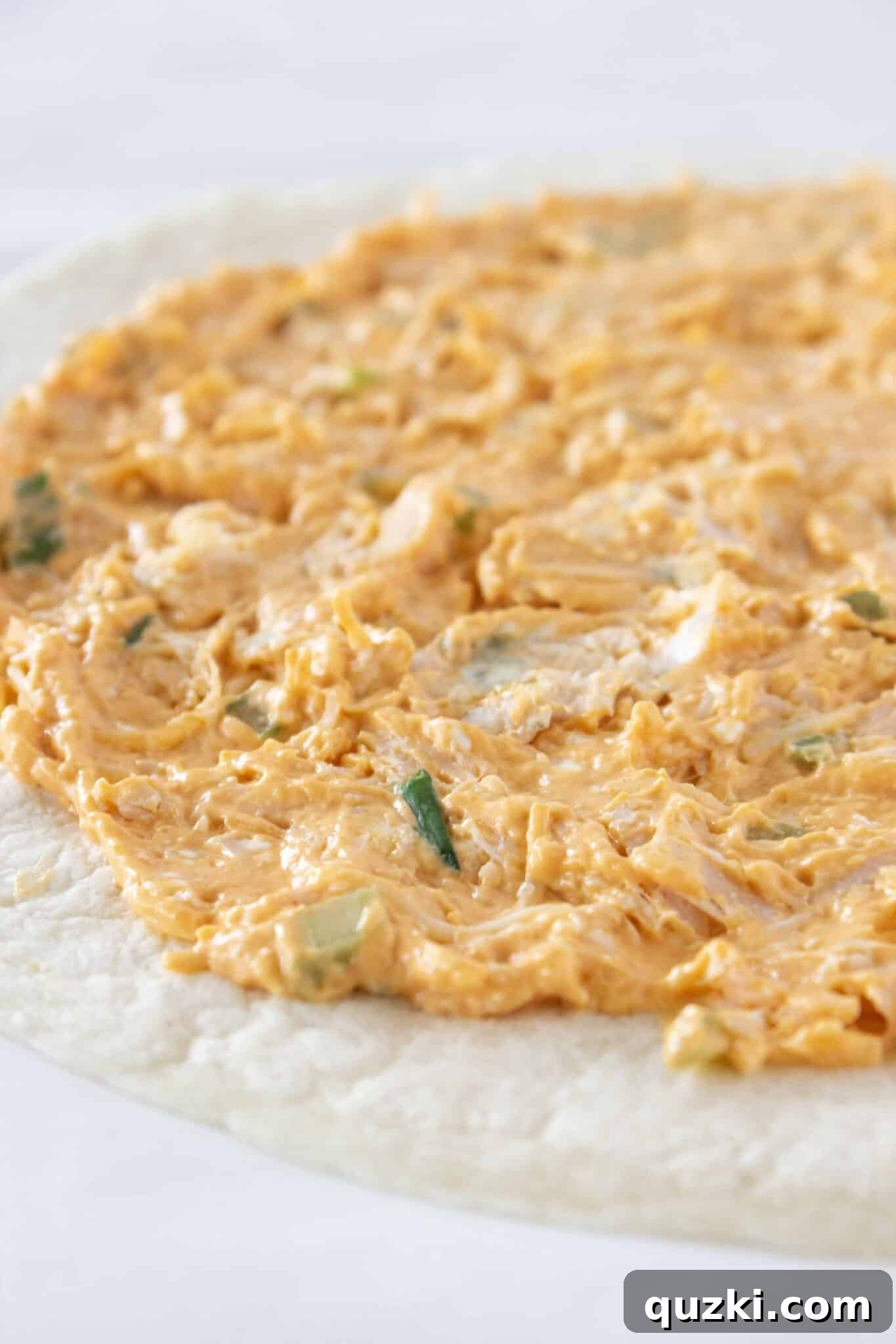 The Ultimate Buffalo Chicken Wrap Recipe 5 Spreading the buffalo chicken filling uniformly on top of a soft flour tortilla.