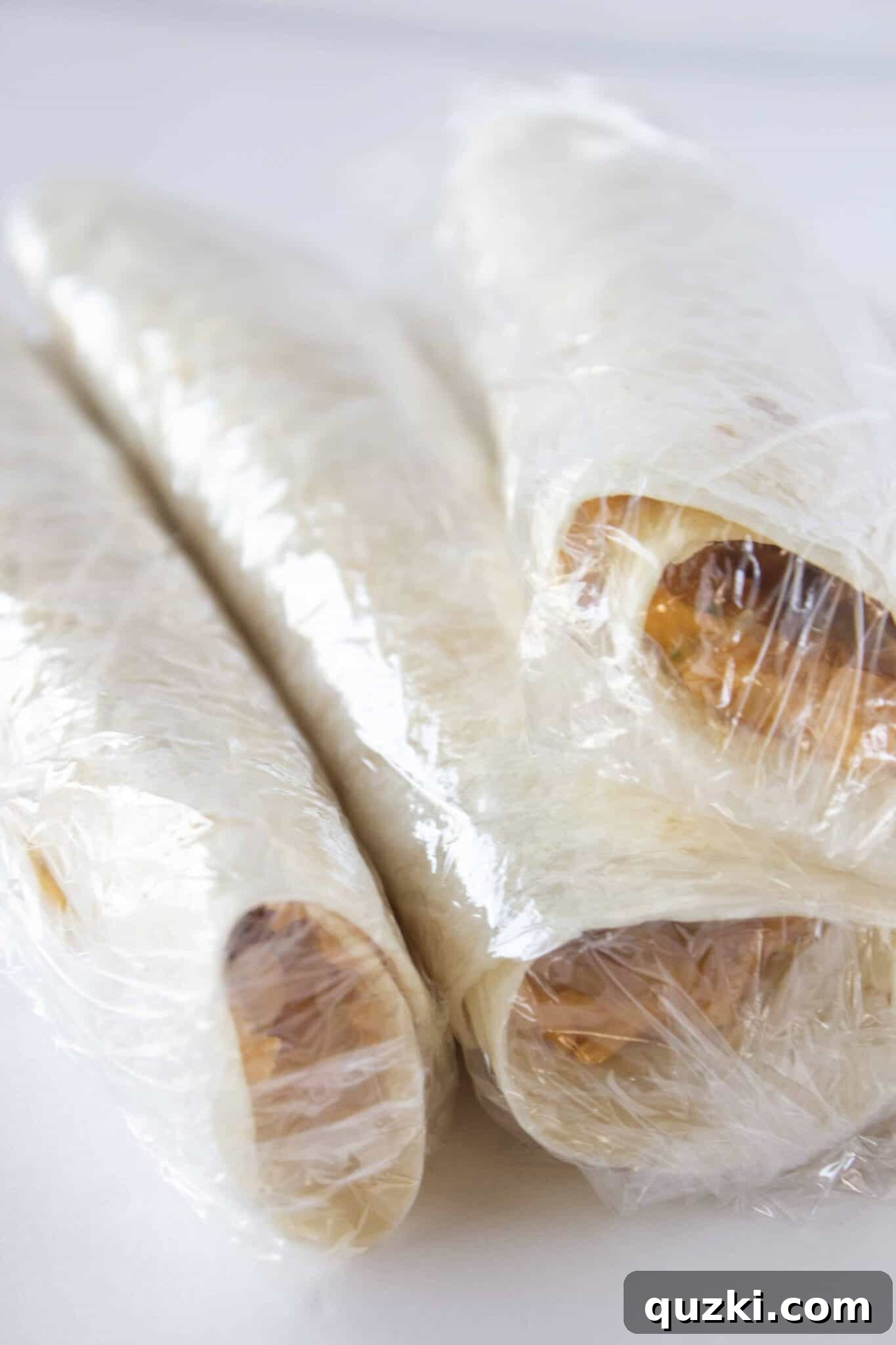 The Ultimate Buffalo Chicken Wrap Recipe 6 Rolling buffalo chicken tortillas tightly and wrapping them in plastic wrap for chilling to set the filling.