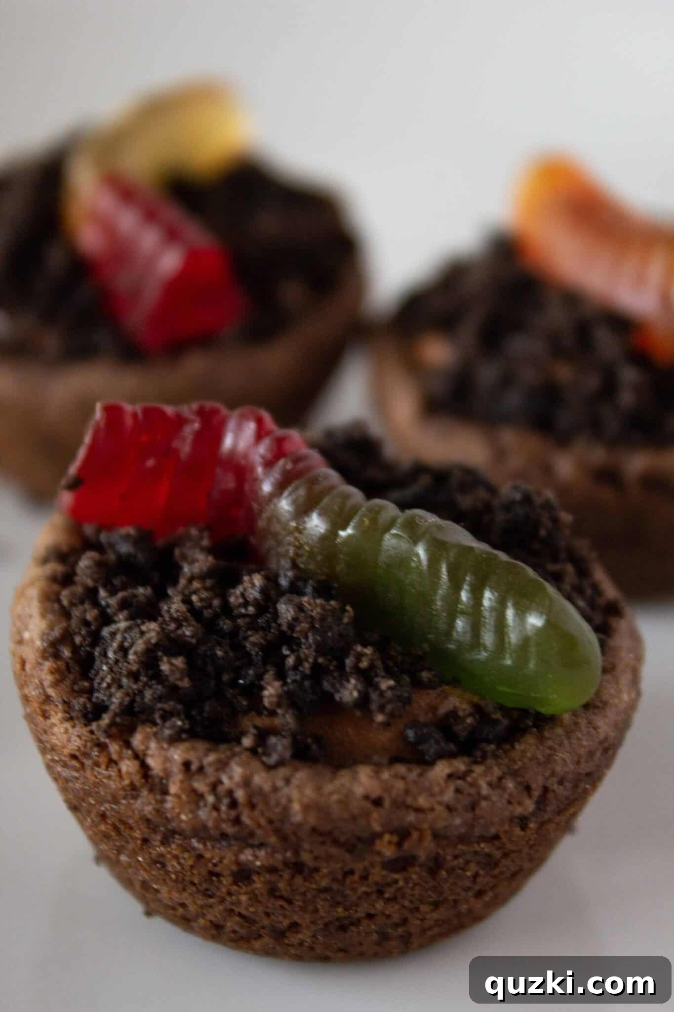 Garden Dirt Cookie Bites 2 Delicious Dirt Cup Cookie Bites arranged on a plate with playful gummy worms peeking out.