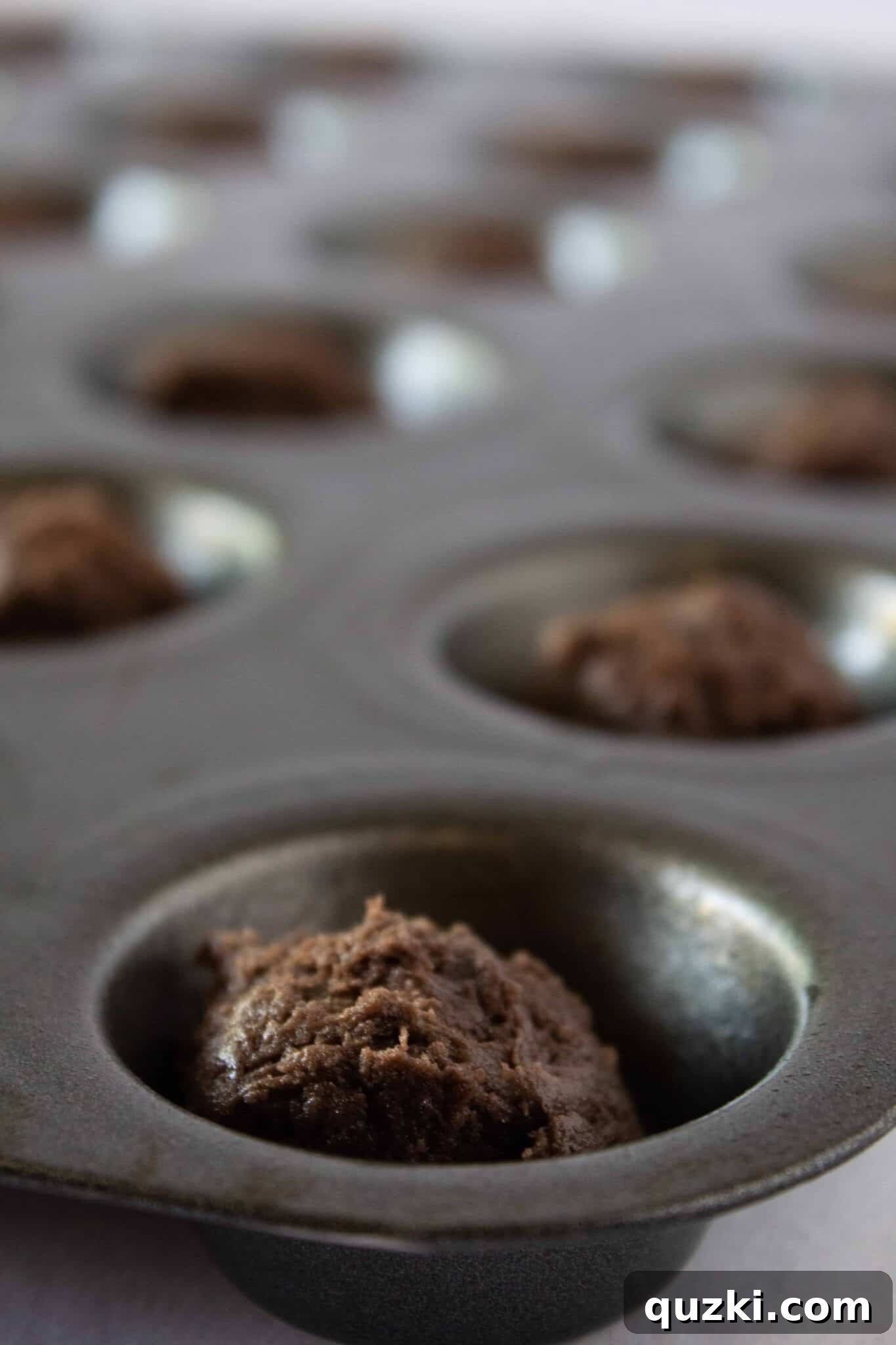 Garden Dirt Cookie Bites 6 Illustrating the process of scooping cookie dough precisely into a mini muffin pan to form the base for Dirt Cup Cookie Bites.