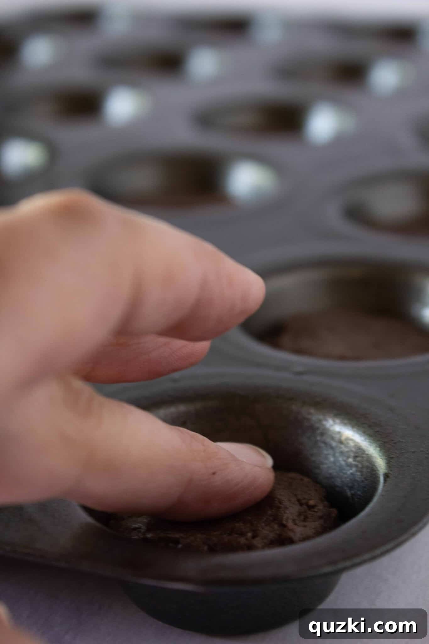 Garden Dirt Cookie Bites 7 Demonstrating how to gently press the cookie dough down with your fingers to create an even layer within each muffin cup.