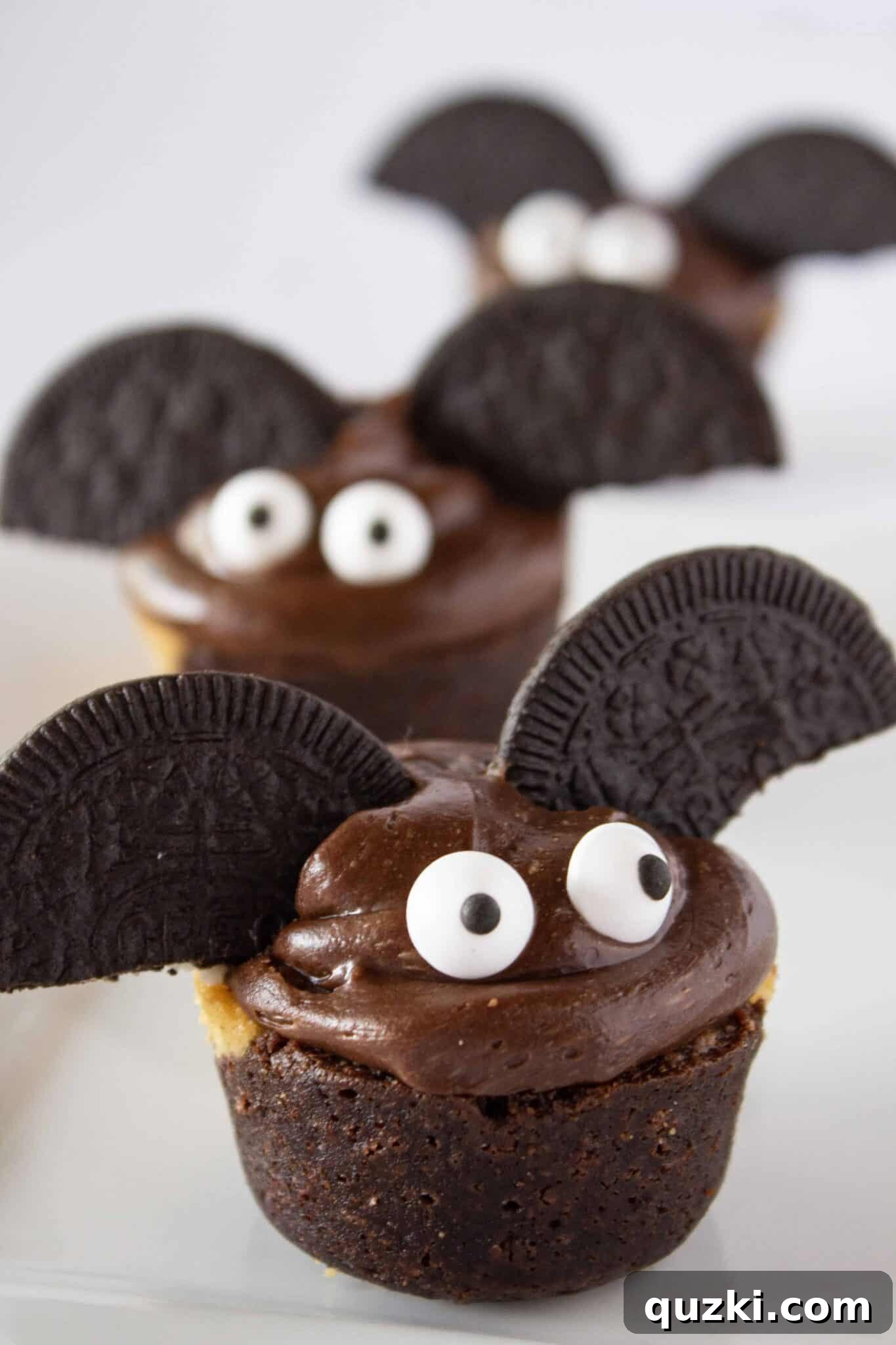 Ghoulish Goodness: Brownie Bat Bites for a Haunting Halloween 2 Delicious Spooky Brownie Bat Bites on a white plate, perfect for Halloween parties and easy dessert ideas.