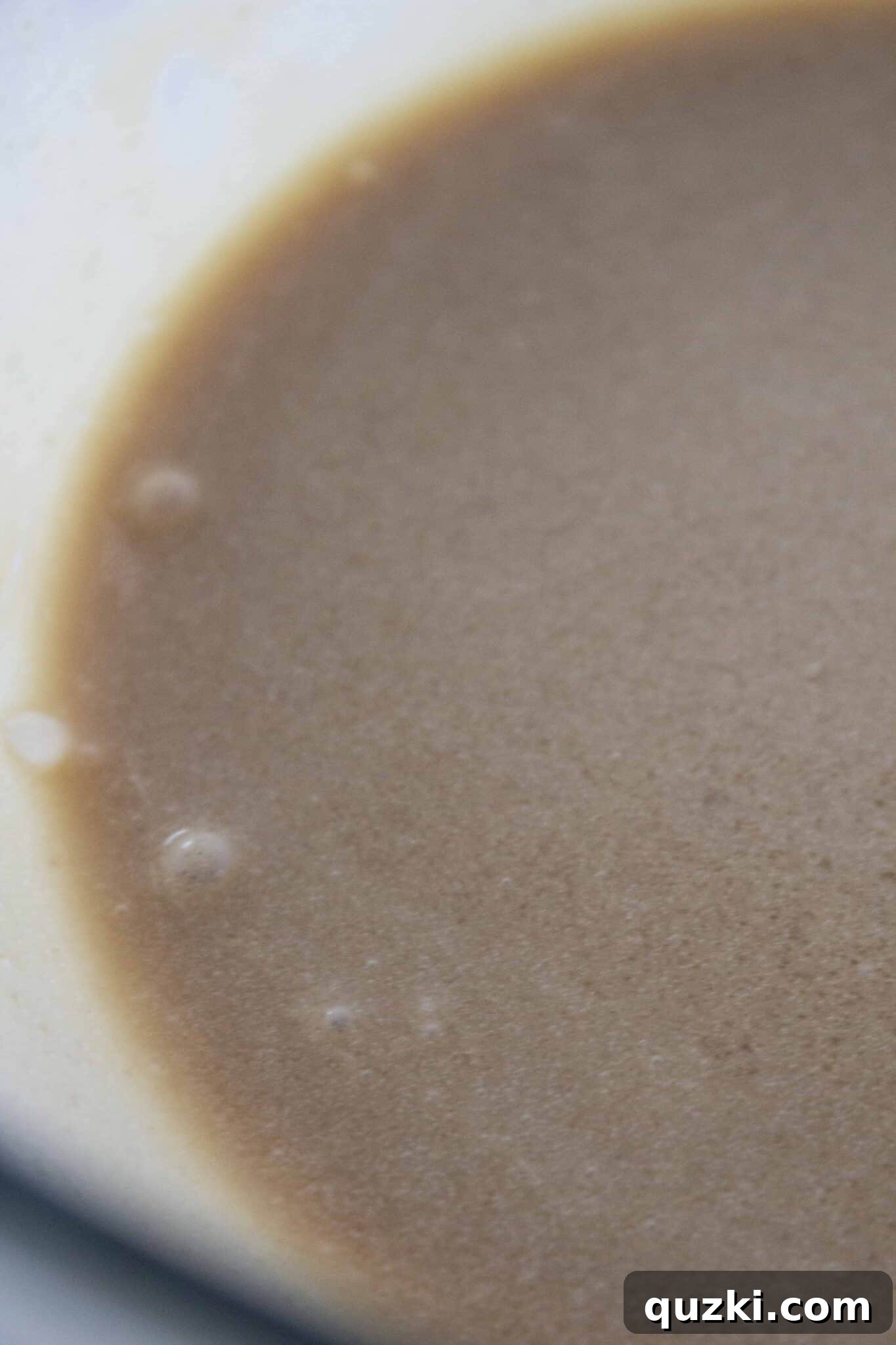 Brown sugar and heavy cream being whisked together for the caramel sauce, a key step in making sticky buns