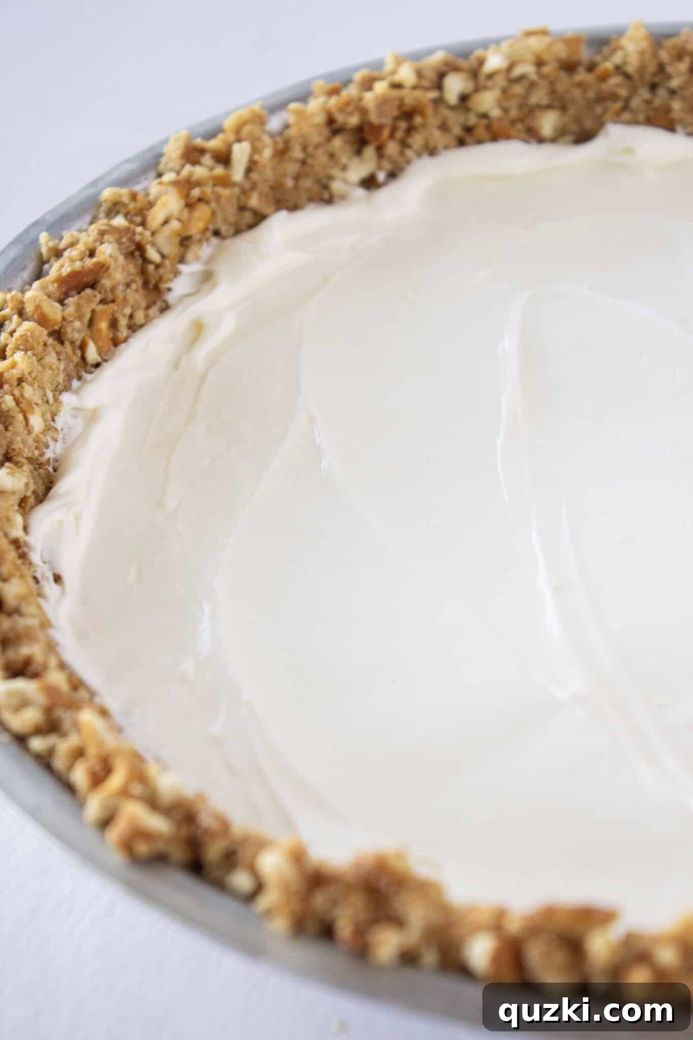 Chilled Raspberry Pretzel Crunch Pie 7 Adding the prepared cream cheese layer to the chilled pretzel pie crust, ensuring an even spread.