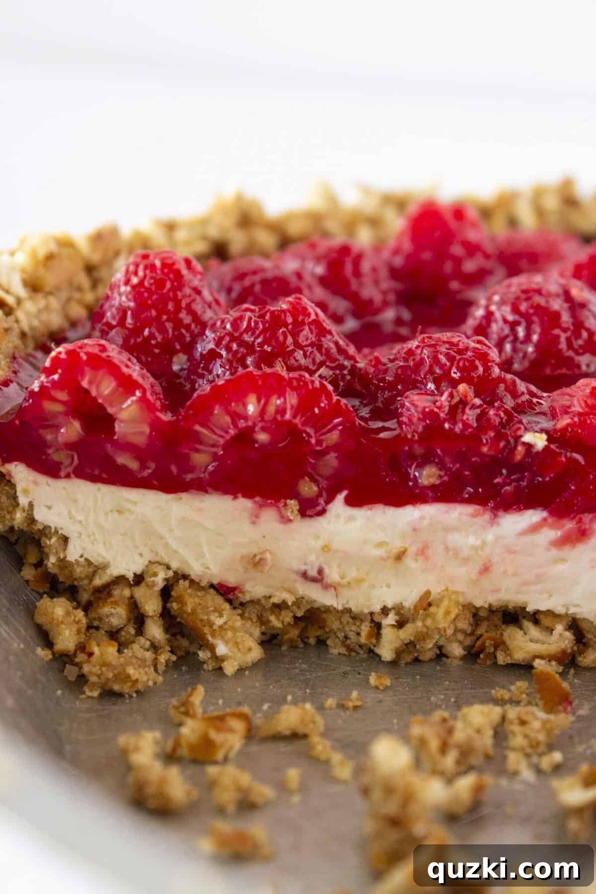 Chilled Raspberry Pretzel Crunch Pie 10 Looking at the inside of a Raspberry Pretzel Pie with cheesecake filling, showing the three distinct layers.