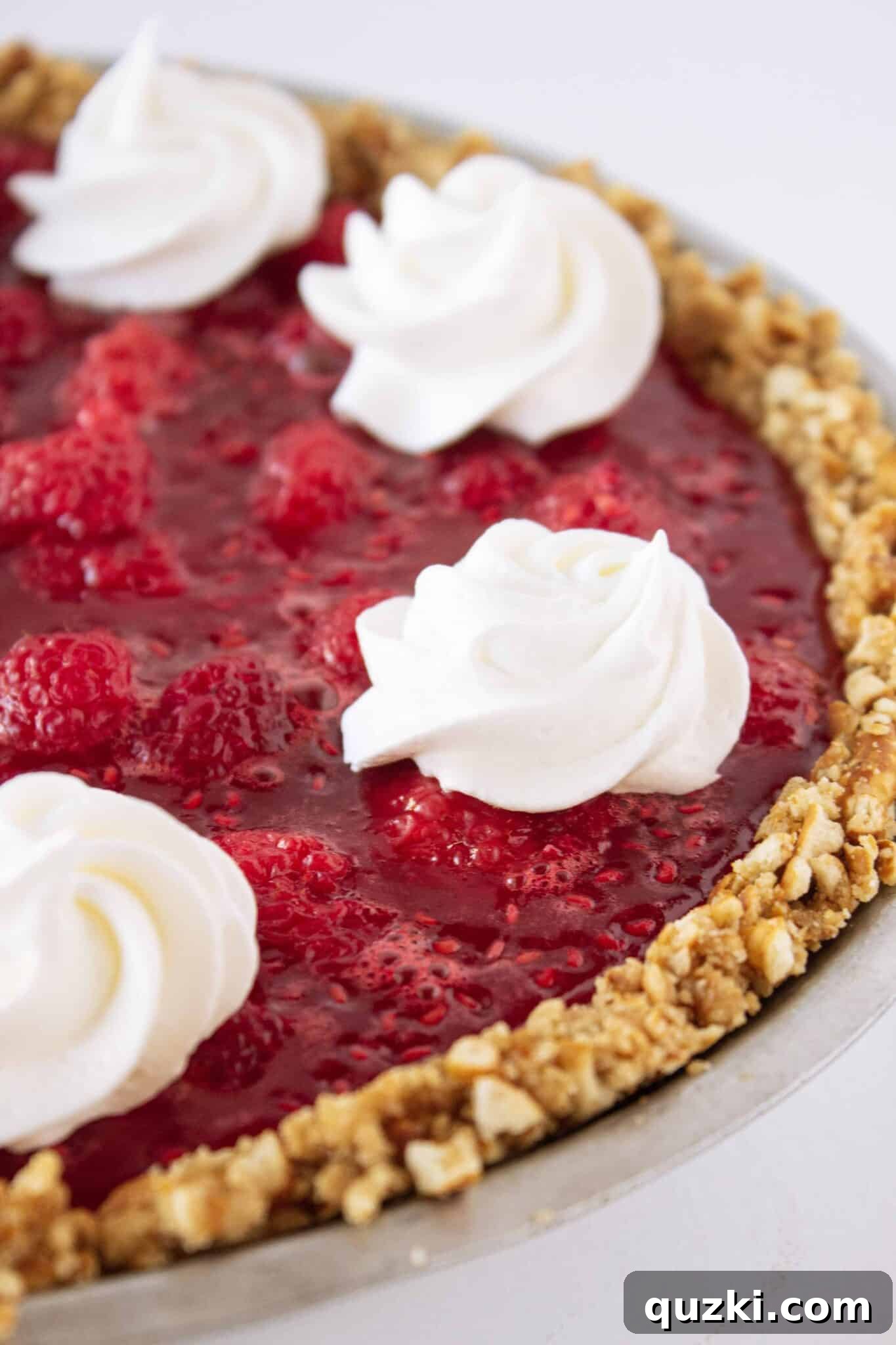 Vibrant No Bake Raspberry Pretzel Pie, showcasing its layered texture with fresh raspberries, featured for its unique sweet and salty taste.
