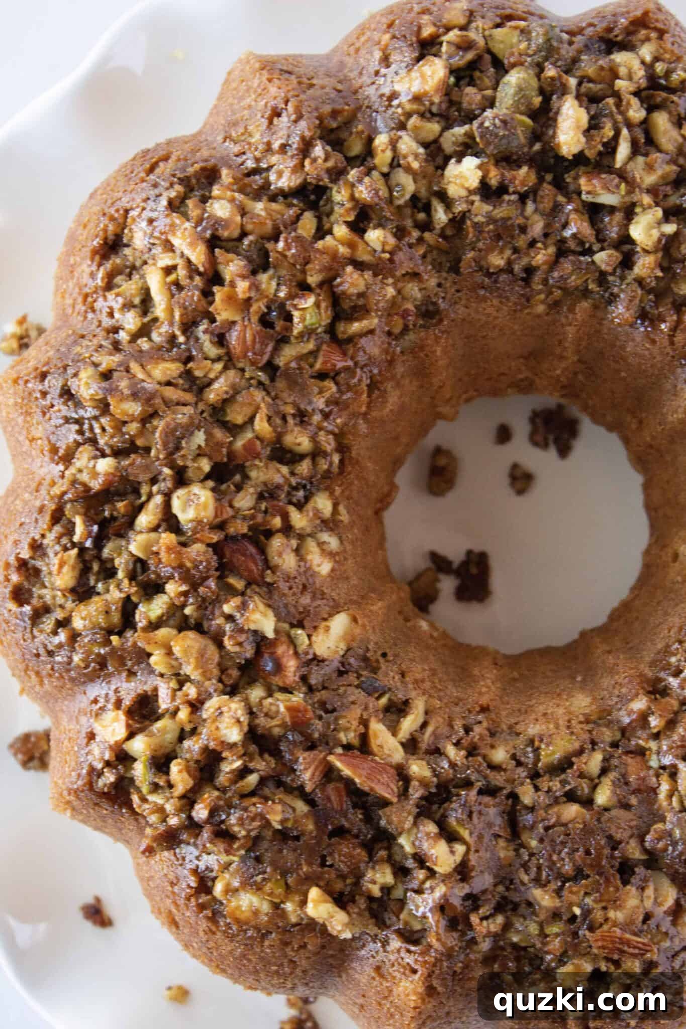 Simple Baklava Bundt Cake with a Cake Mix Shortcut 7 Inverting the Baklava Bundt Cake onto a cake plate, showcasing the nutty top