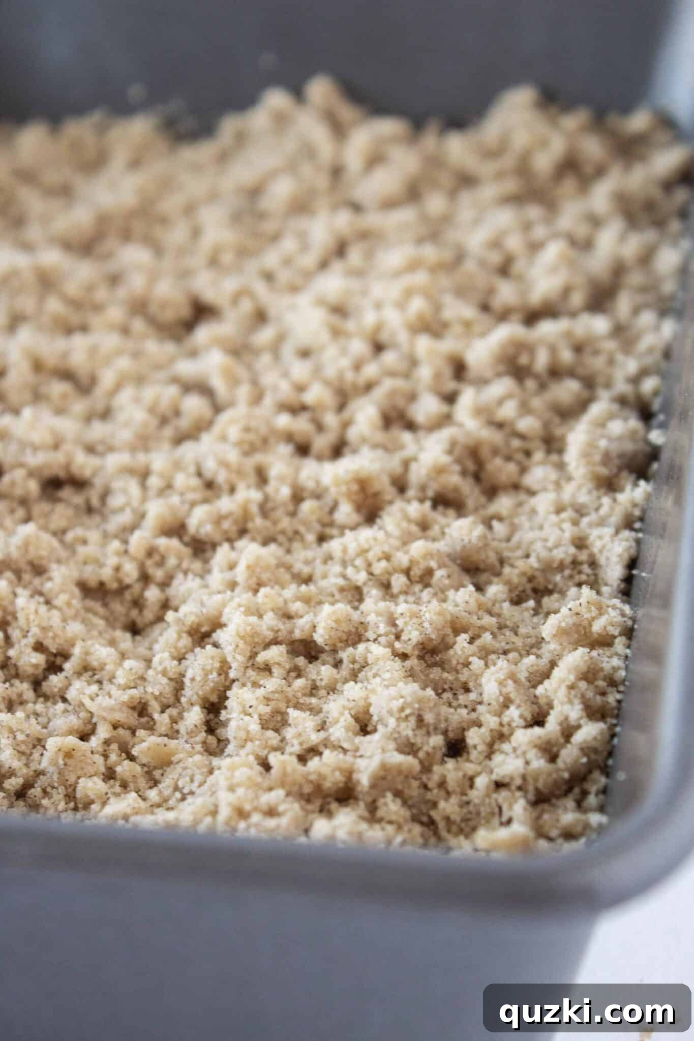 Sweeten Your Christmas Morning: Eggnog Coffee Cake 7 Applying a generous layer of spiced crumb topping to the Eggnog Coffee Cake batter.