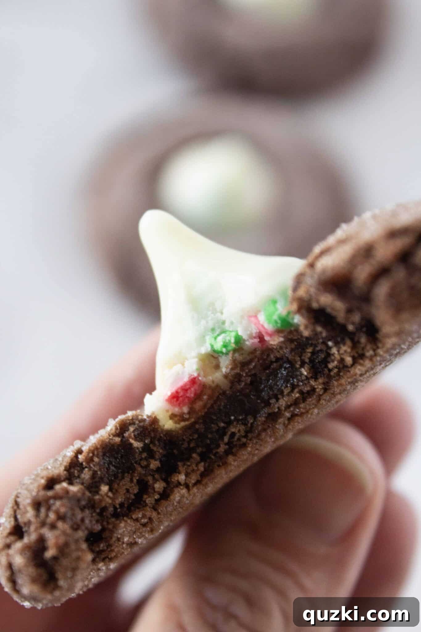 A Chocolate Kiss Cookie with a bite taken from it, revealing the sugar cookie filling.