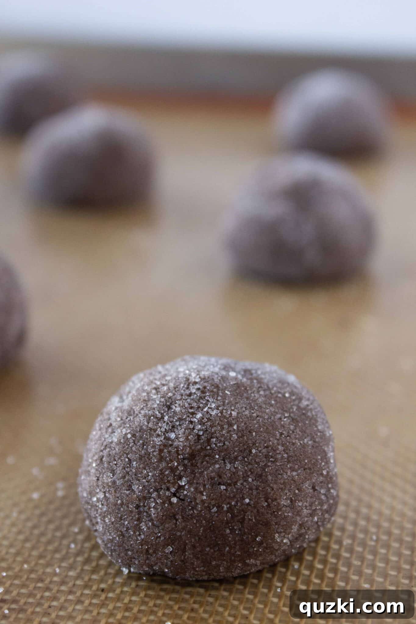Making the chocolate cookie dough and rolling the balls in granulated sugar, showing the preparation process.