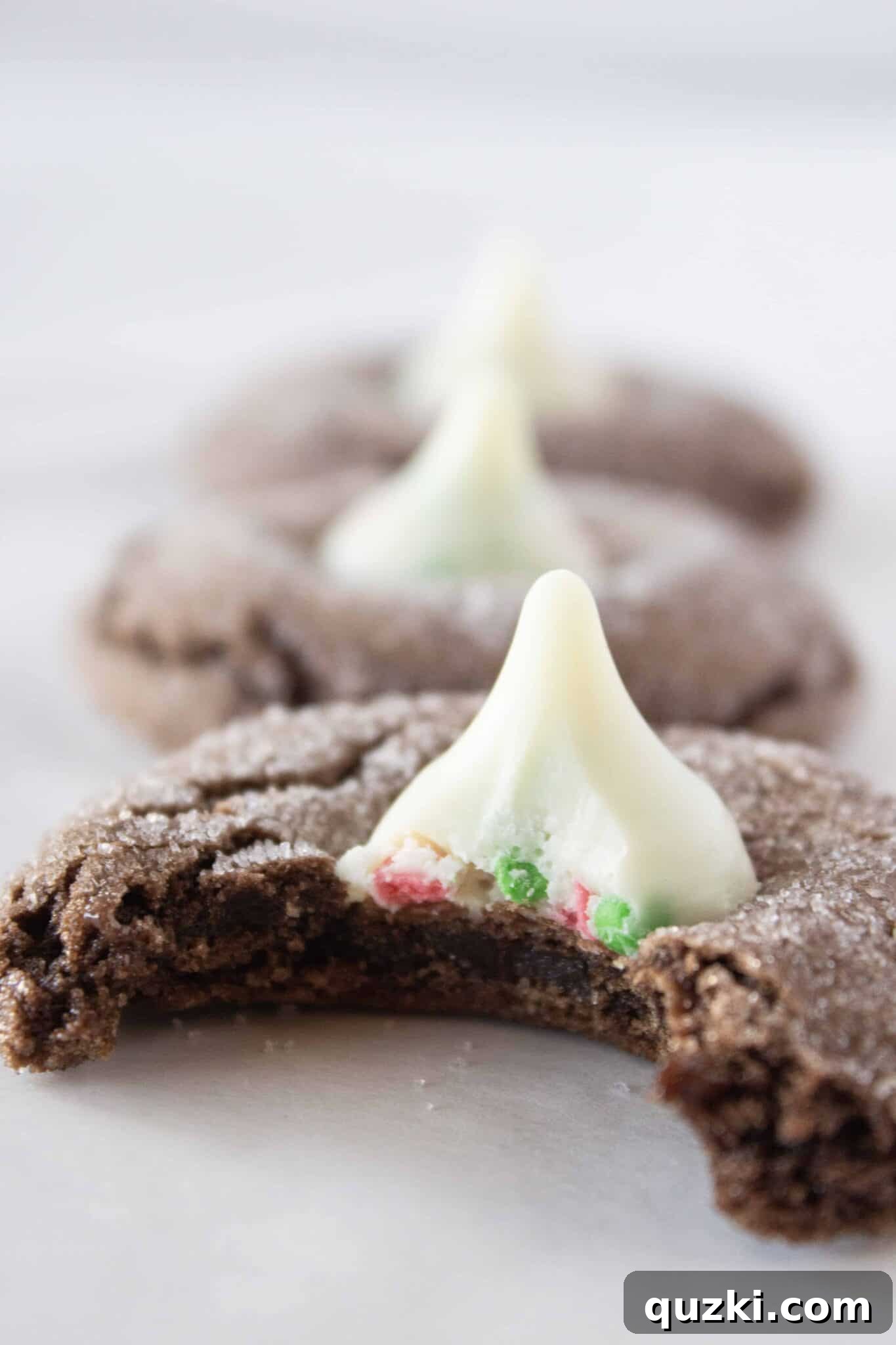 Chocolate Kiss Cookies in a row with a bite taken from the first one, showcasing the perfect texture.