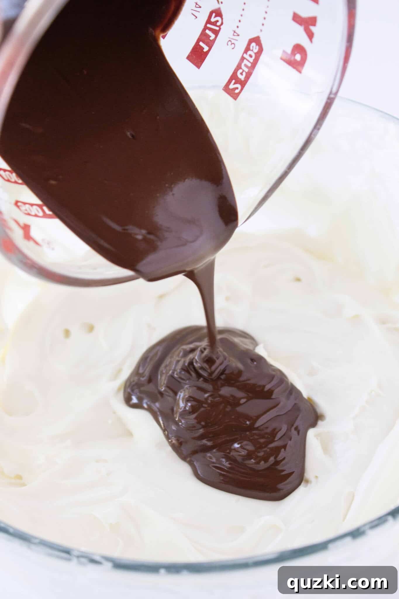 Folding melted chocolate into a portion of the creamy cheesecake batter.