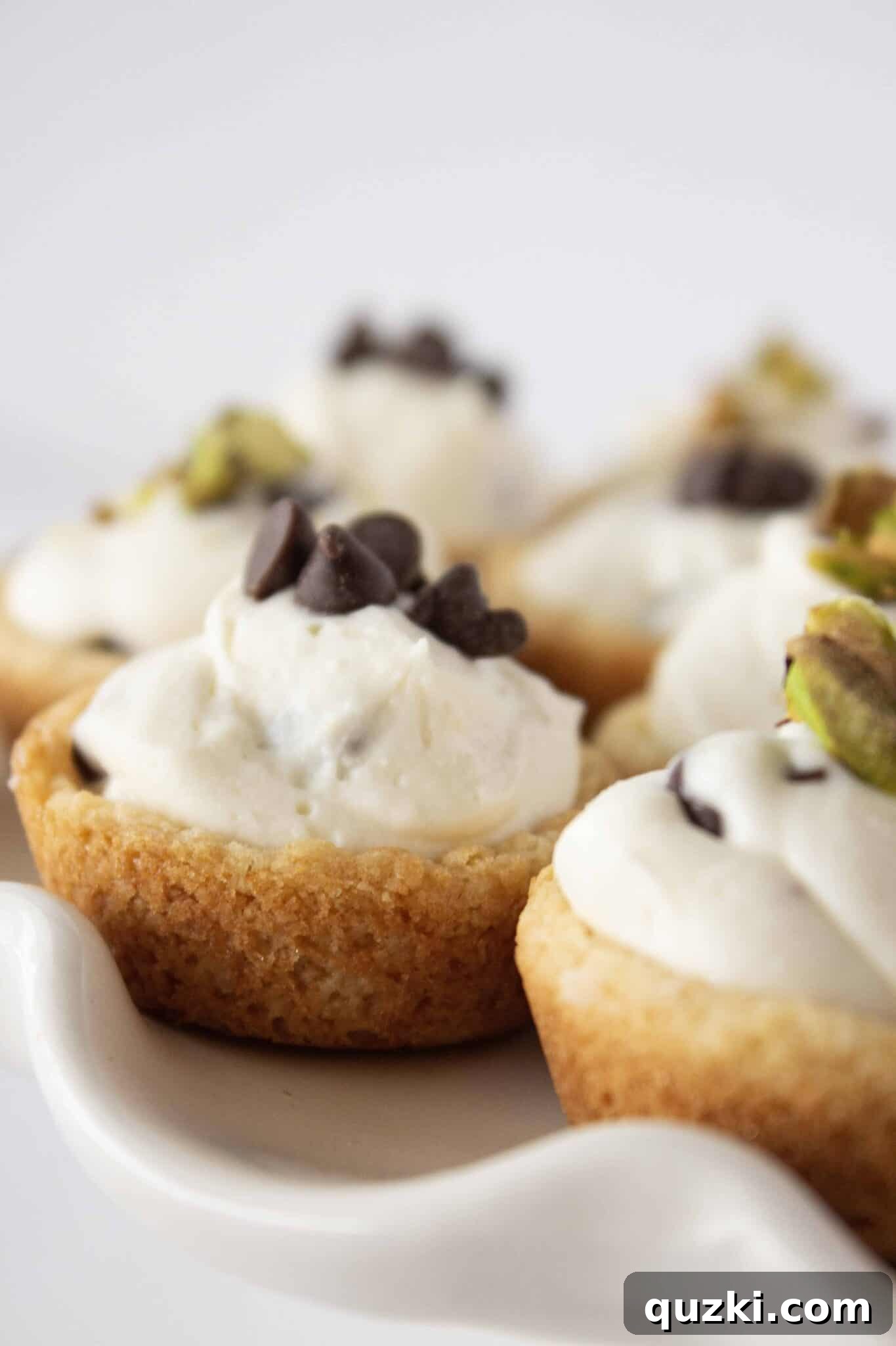 Serving Cannoli Cookie Cups on a pristine white cake plate, highlighting their elegant presentation.