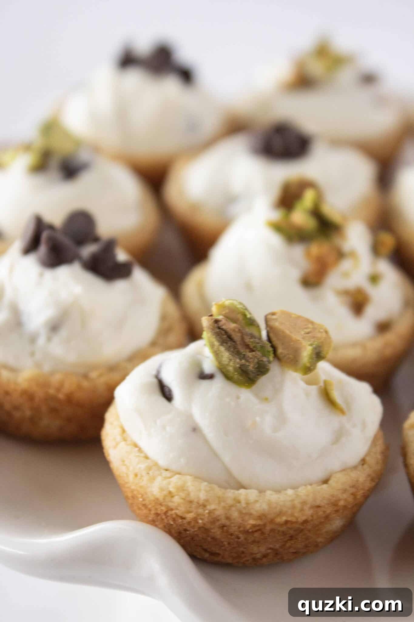 Cannoli cookie cups artfully arranged on a tray, generously topped with chopped pistachios and mini chocolate chips.