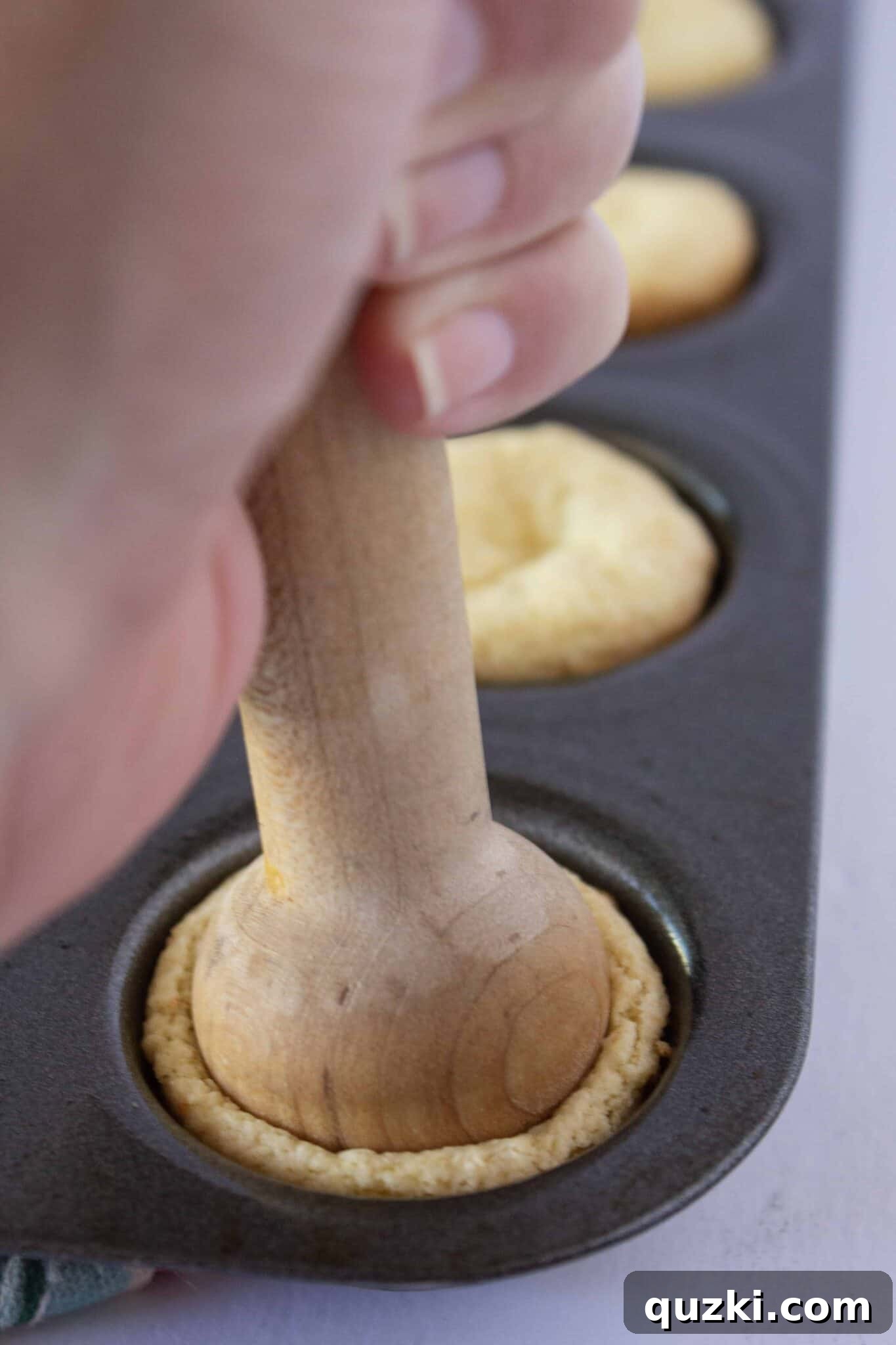 Pressing down on the center of each warm cookie with a tart shaper to create a perfect indentation for the filling.