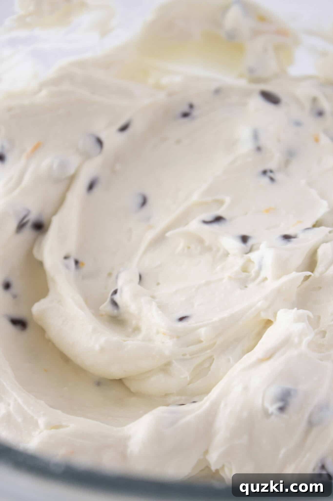 Gently folding mini chocolate chips into the creamy cannoli filling for the cookie cups.