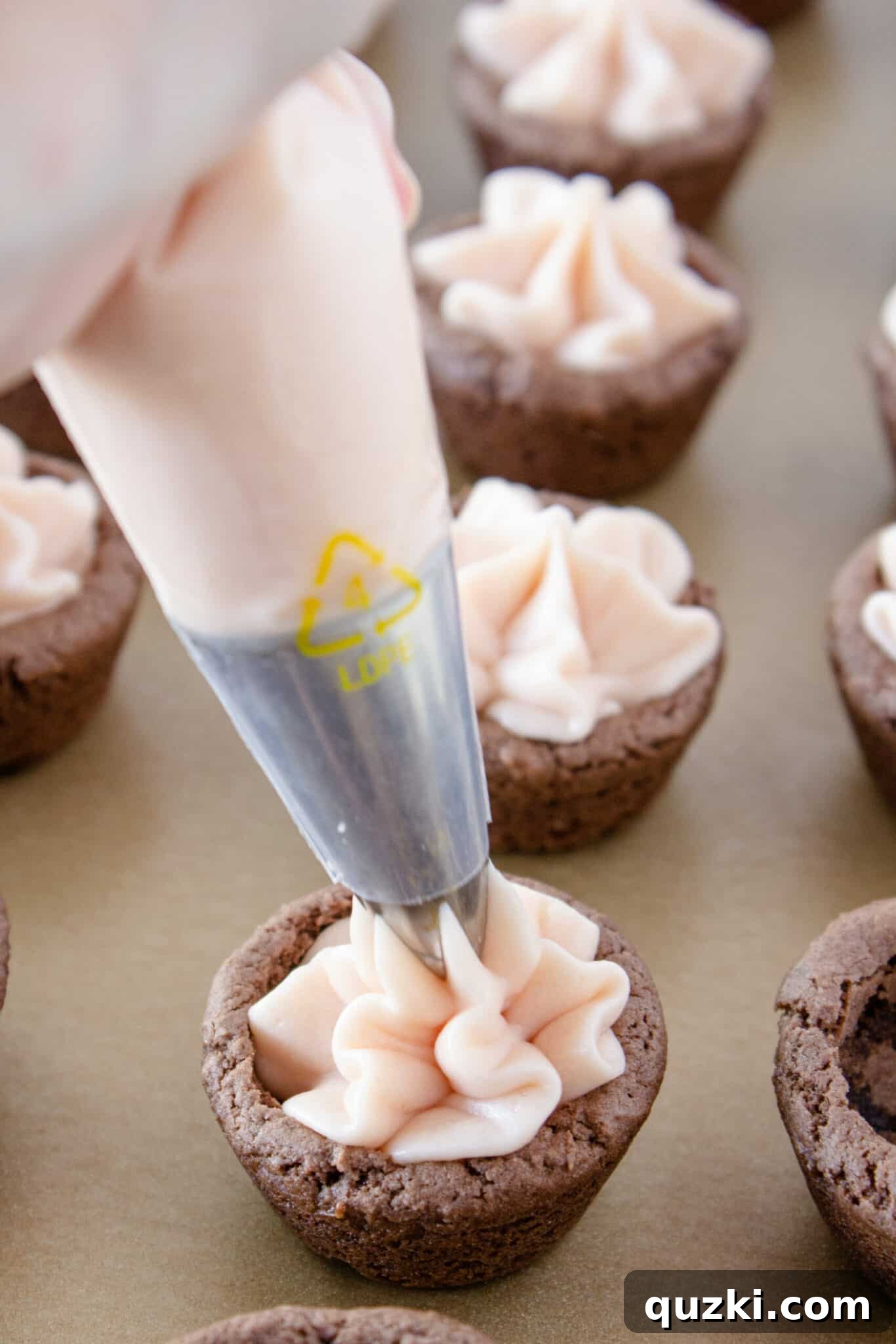 Luscious Chocolate Dipped Strawberry Cookie Cups 13 Strawberry buttercream being piped into a chocolate cookie cup, creating a creamy filling.