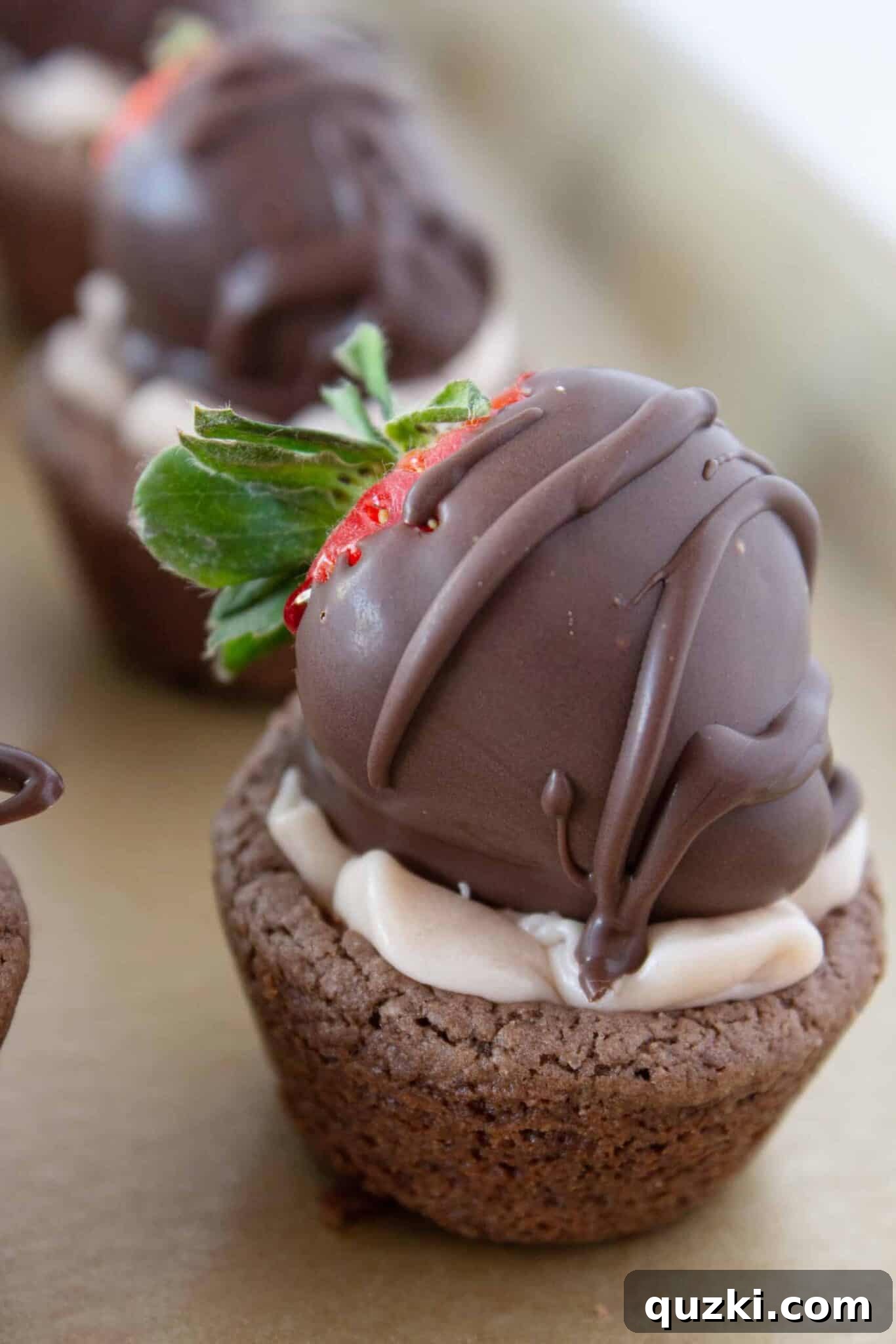 Luscious Chocolate Dipped Strawberry Cookie Cups 14 A chocolate covered strawberry being placed on top of a cookie cup filled with strawberry buttercream, completing the dessert.