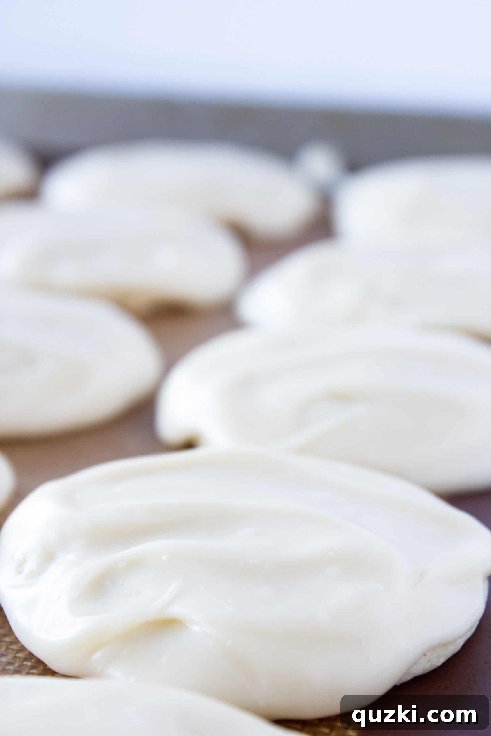Cake Mix Magic: White Sheet Cake Cookies 8 White Sheet Cake Cookies being glazed with a spoonful of smooth, white frosting.