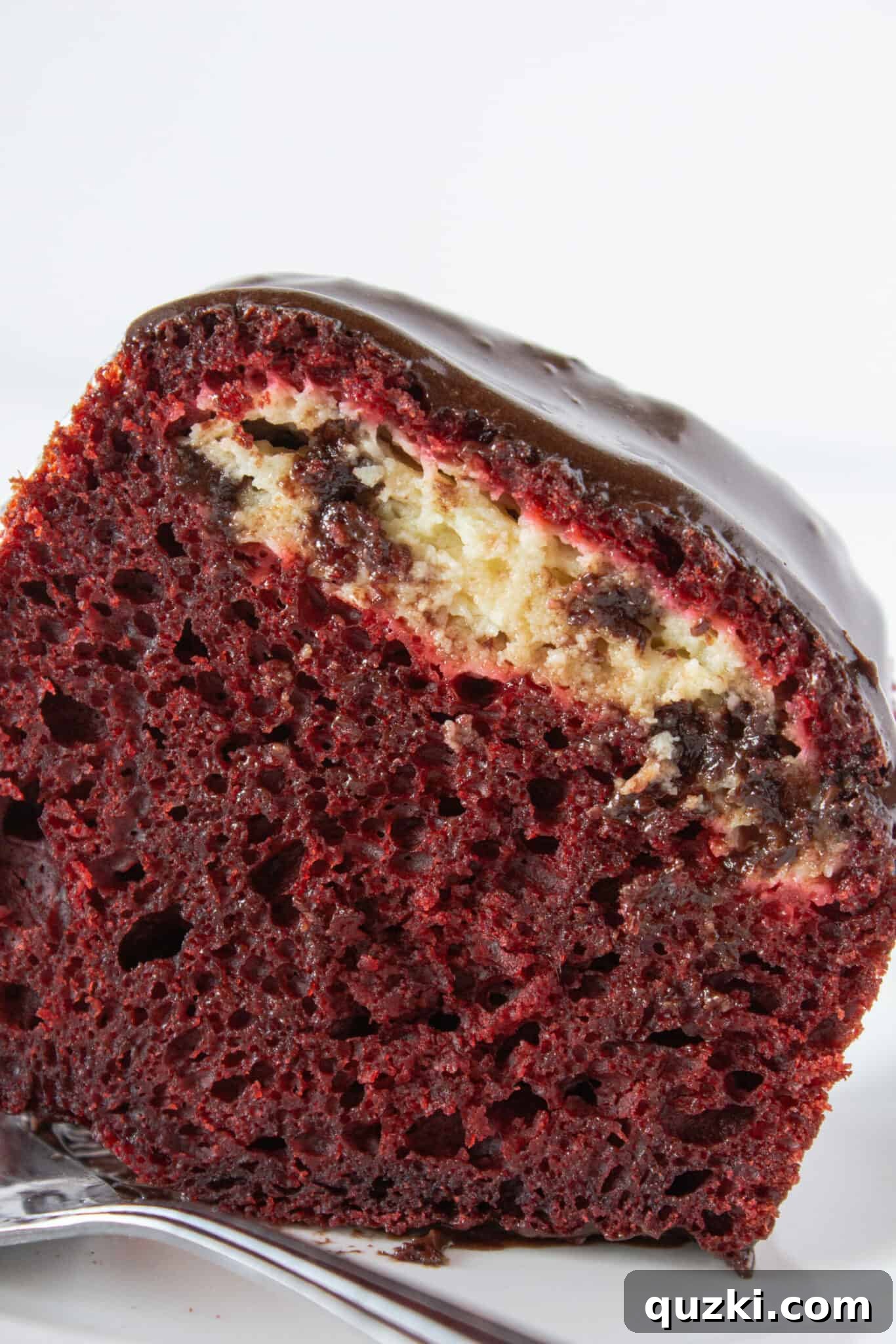 Black Bottom Red Velvet Bundt Cake Made Easy 2 A slice of red velvet black bottom cake with chocolate glaze, showing the distinct layers.