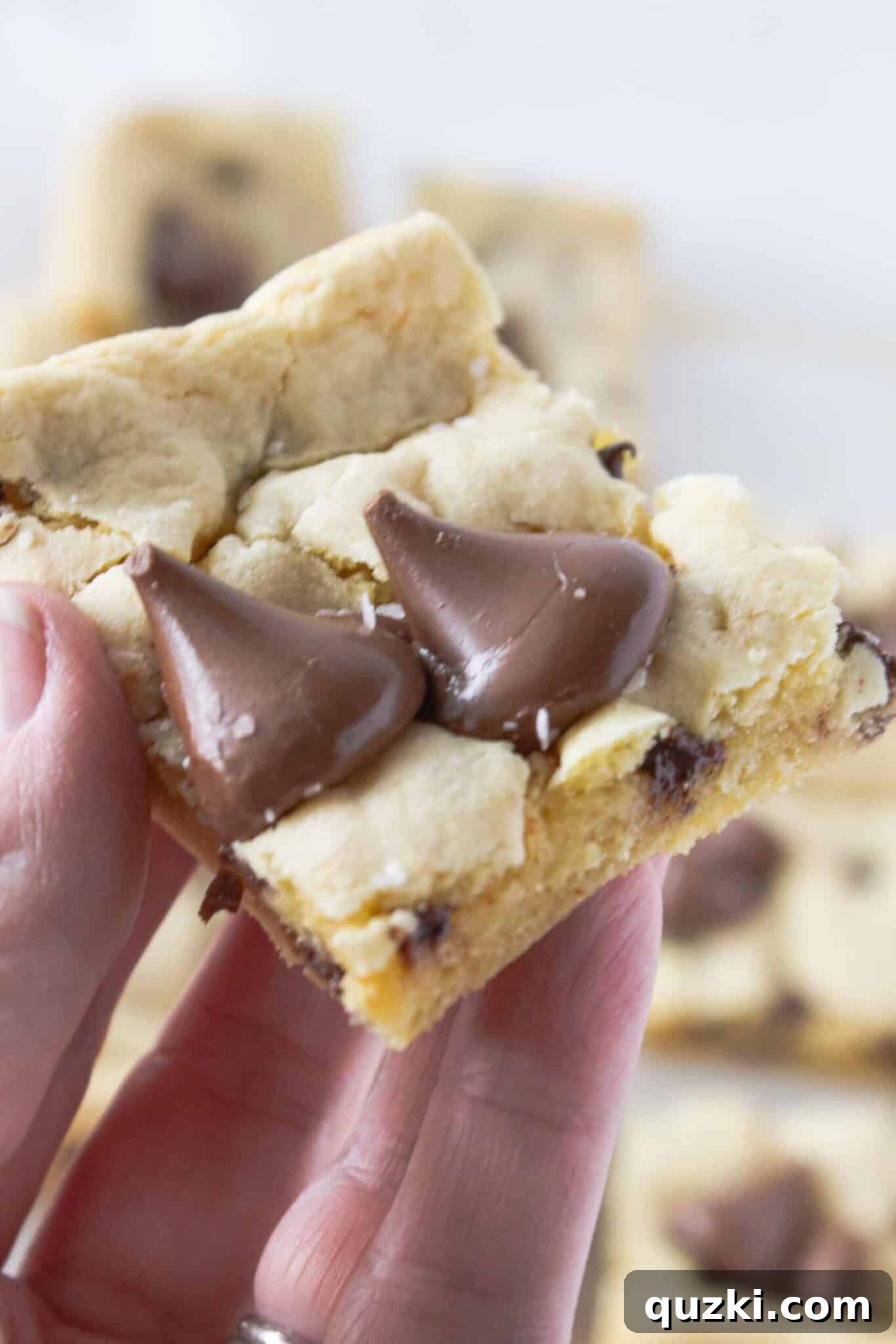 Toasted Butter Hershey Kiss Cookie Bars 10 A single delicious Brown Butter Hershey's Kiss Cookie Bar held in a hand, ready to be devoured.