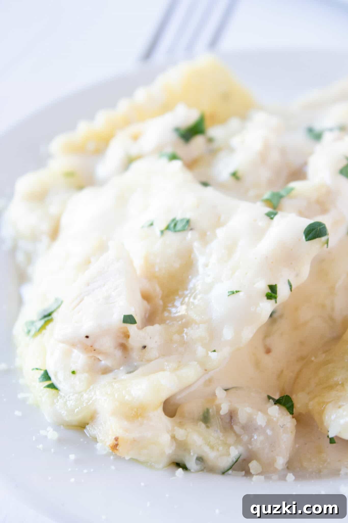 Creamy Chicken Alfredo Ravioli Bake 2 Chicken Alfredo Ravioli Bake being served for dinner. Golden-brown cheese topping with creamy ravioli and chicken beneath.