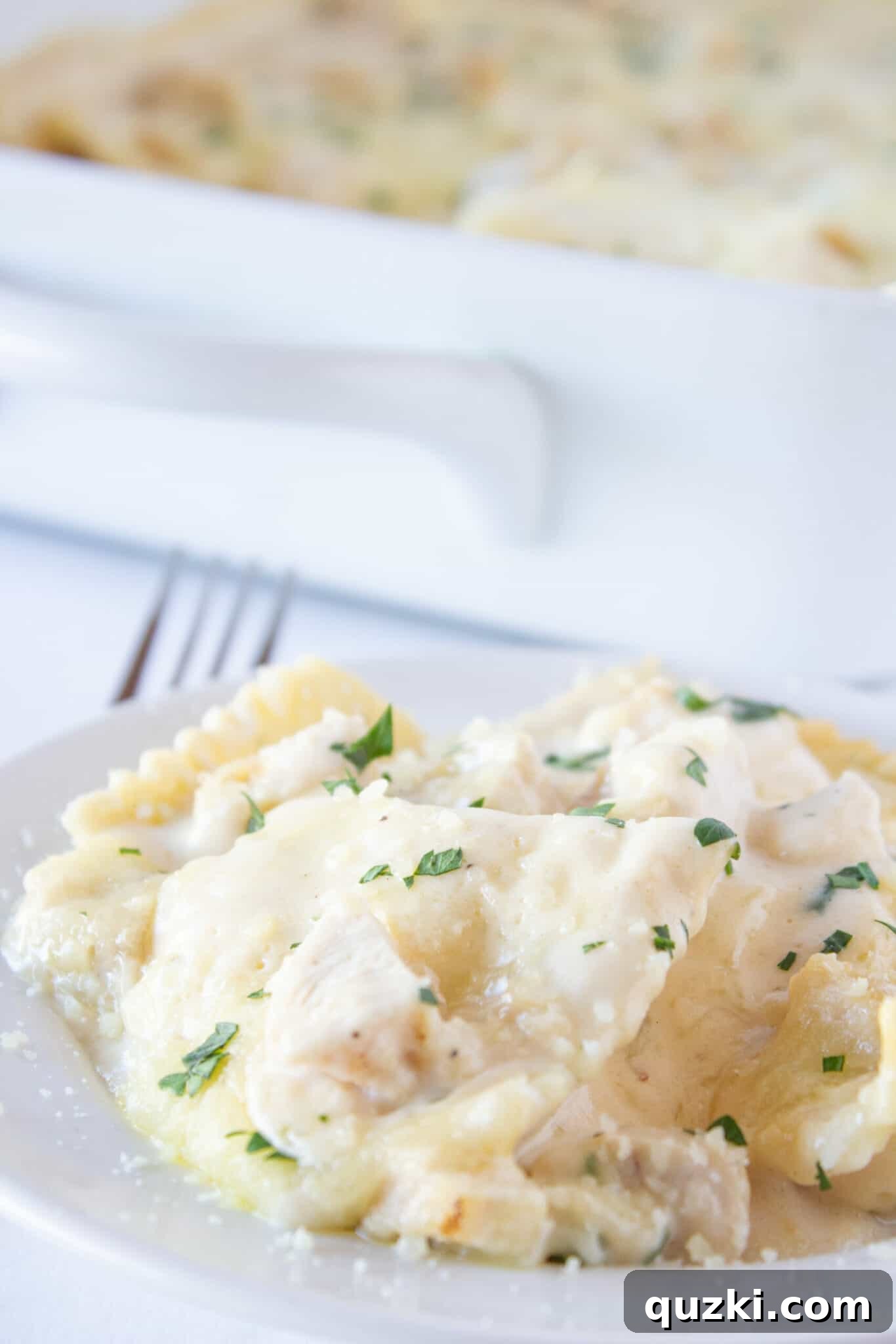 Creamy Chicken Alfredo Ravioli Bake 10 Serving a generous portion of Chicken Alfredo Ravioli Bake on a white plate, highlighting the melted cheese and flavorful contents.