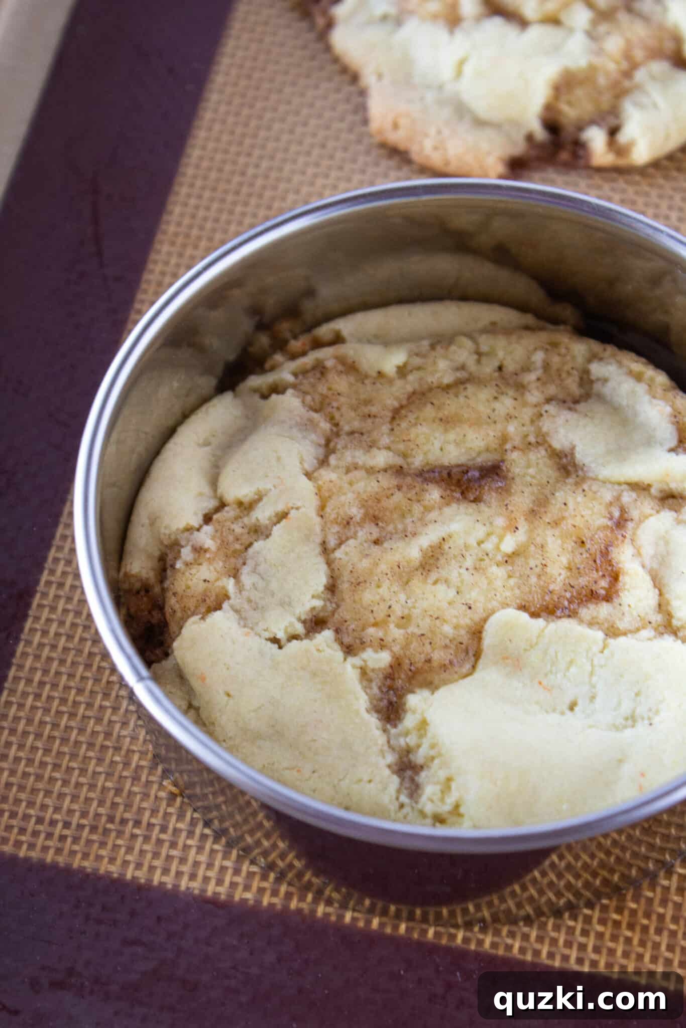 Baked cinnamon roll cookies showing their internal swirl, with glaze