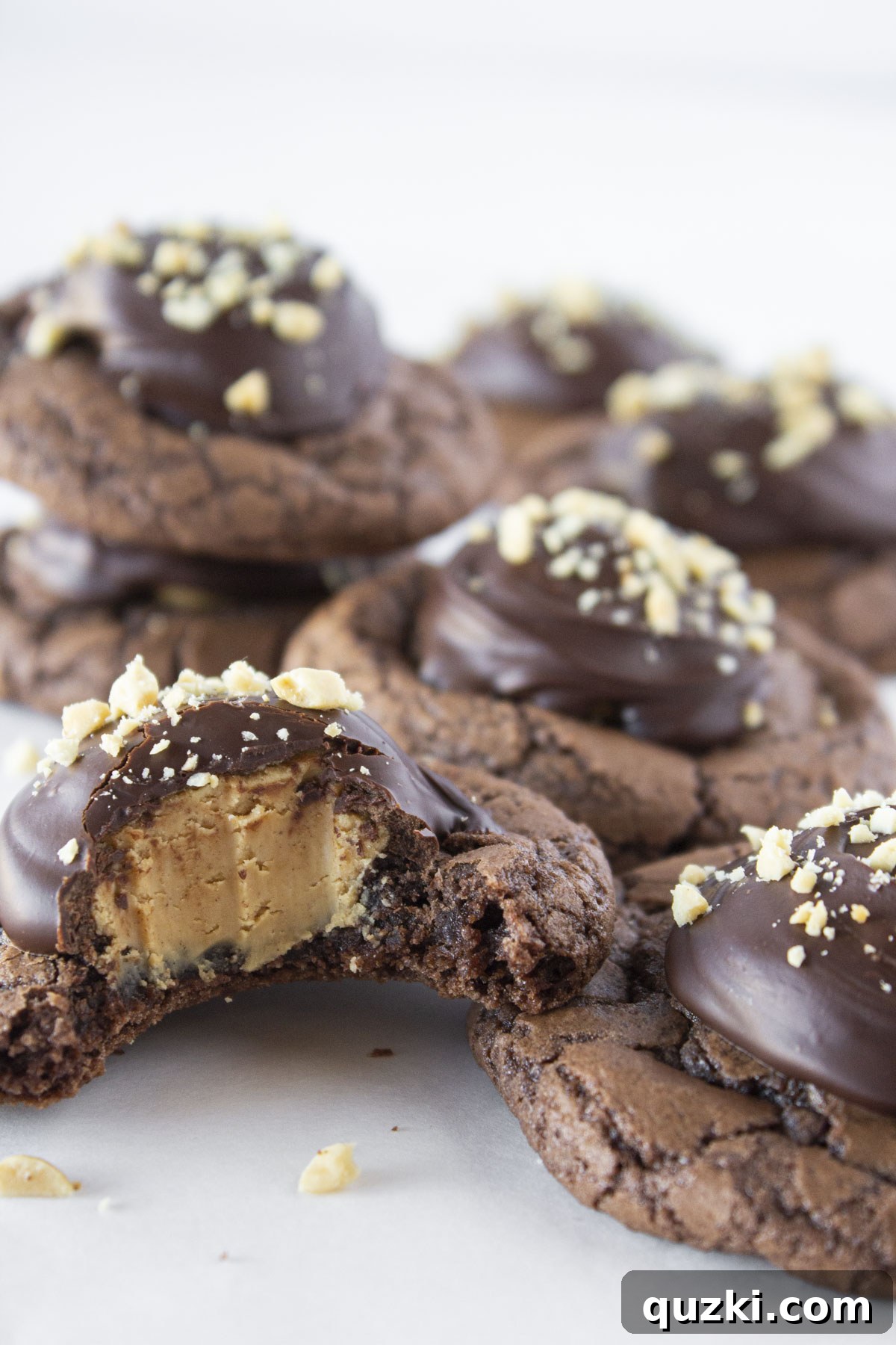 Simple Buckeye Brownie Indulgence 8 Seven Buckeye Brownie Cookies stacked and arranged on a white plate with one having a bite taken out of it, clearly revealing the peanut butter center and chocolate topping.
