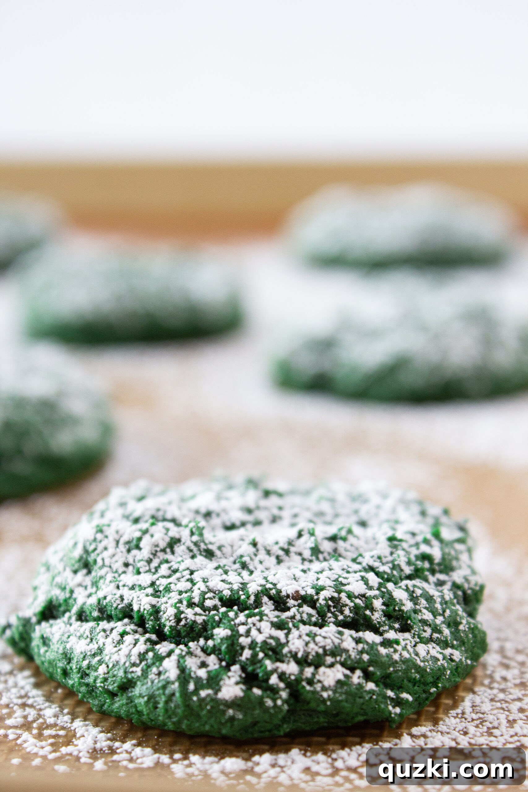 Effortless Green Velvet Cake Mix Cookies 8 Powdered sugar dusted Green Velvet Cream Cheese Cookies on a plate.