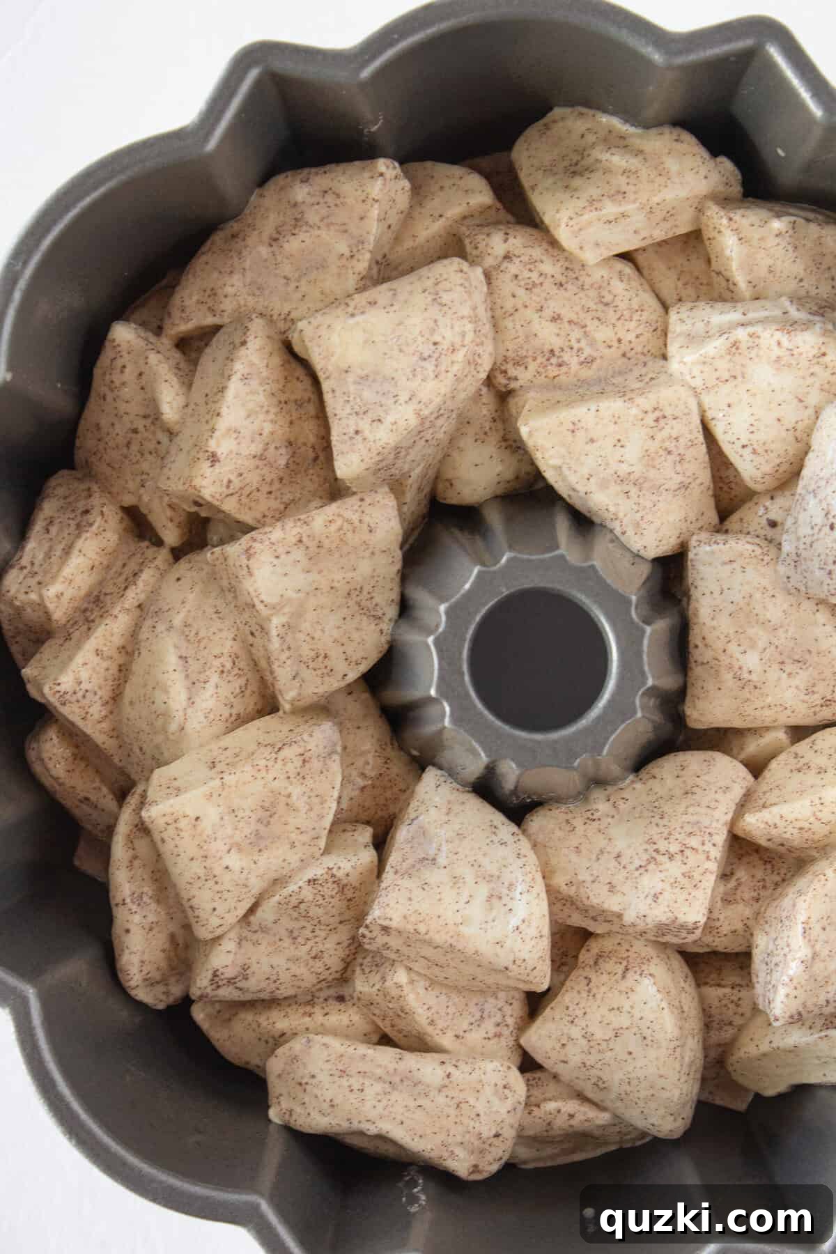 Adding the coated refrigerated biscuits to a prepared bundt pan.