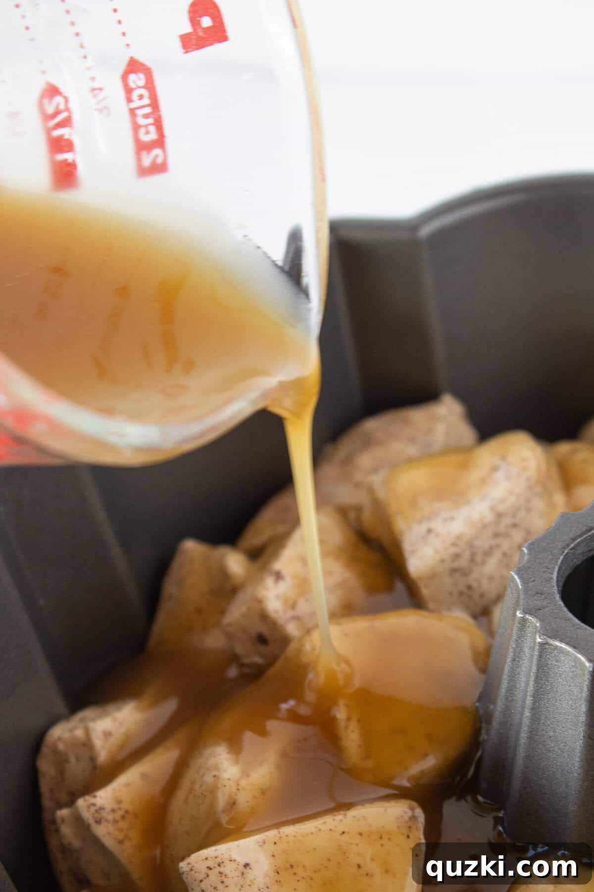 Pouring a melted butter mixture over the french toasted batter covered biscuits.