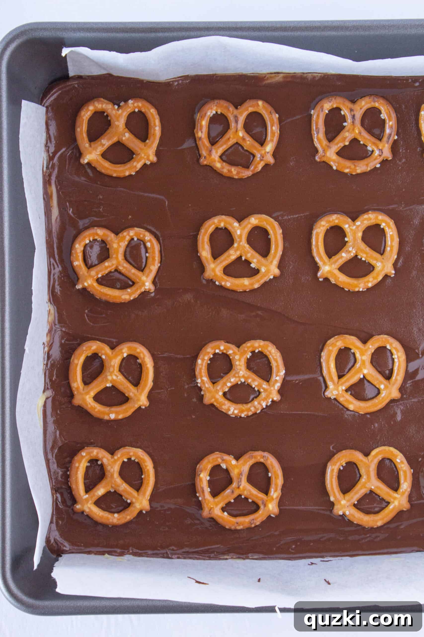 Placing mini pretzels on top of the melted chocolate layer for Millionaire Bars