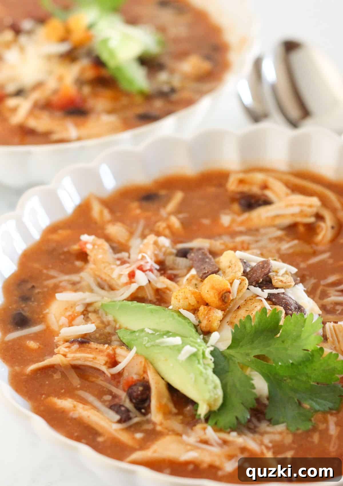 Effortless 20 Minute Chicken Enchilada Soup 2 Two steaming bowls of chicken enchilada soup, garnished with fresh toppings like avocado, cilantro, and tortilla strips.