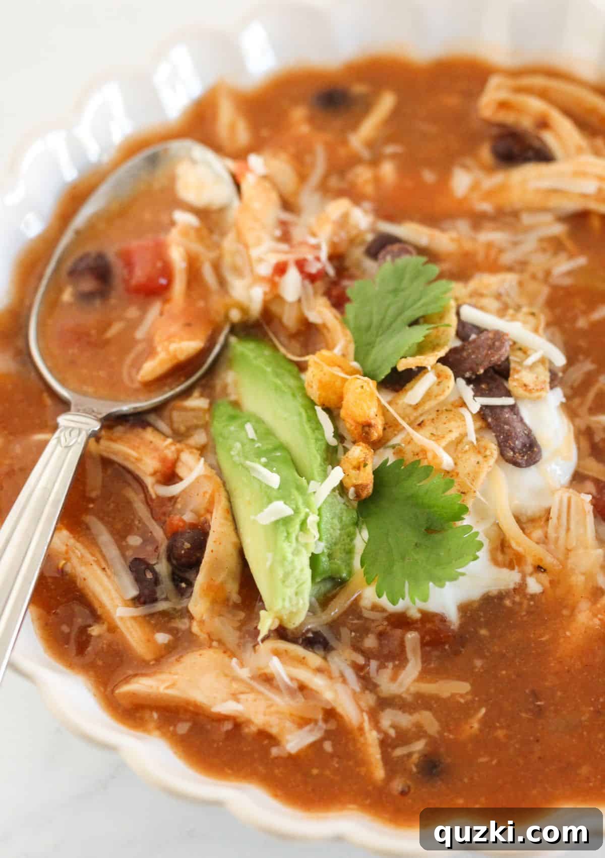 Effortless 20 Minute Chicken Enchilada Soup 8 A person enjoying a bowl of chicken enchilada soup with various toppings, emphasizing the customizable and satisfying nature of the meal.