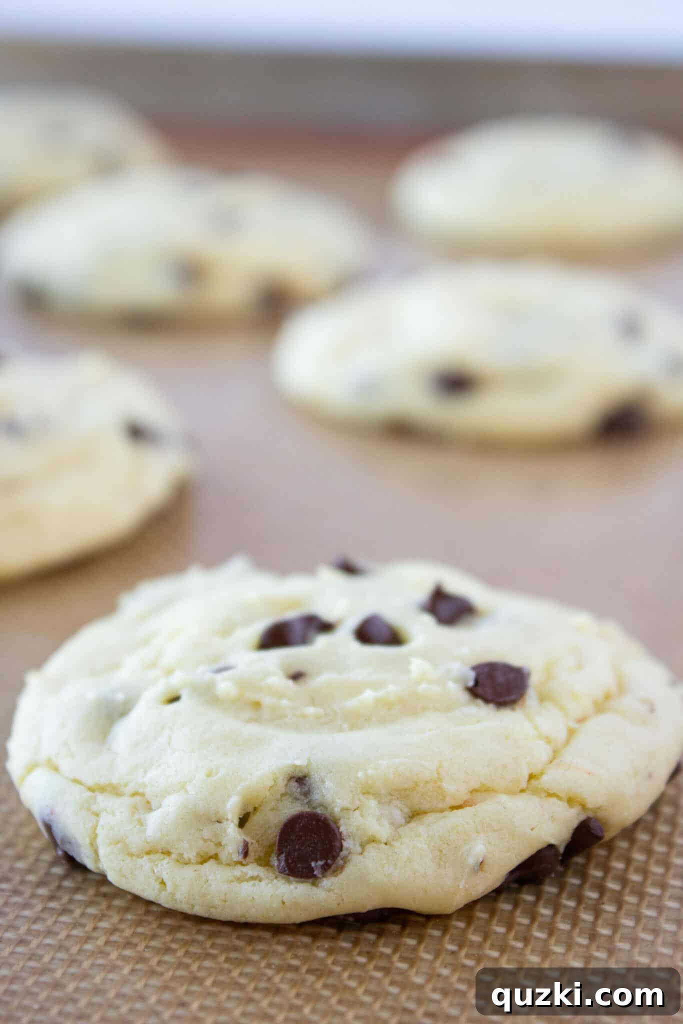 Freshly baked Chocolate Chip Sheet Cake Cookies cooling on a baking sheet, ready for frosting.