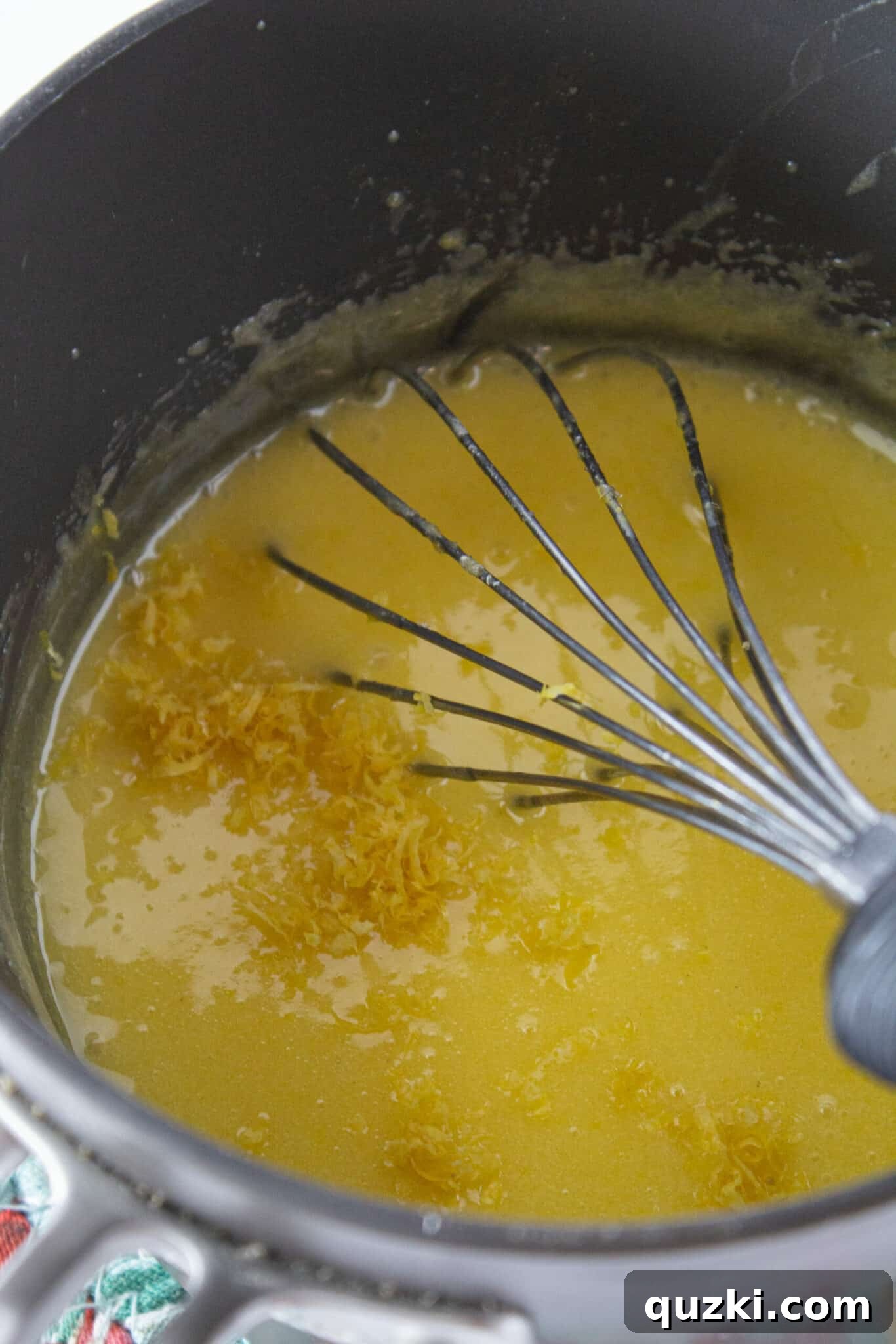 Homemade lemon filling being cooked in a saucepan, showcasing its creamy texture as it thickens to perfection.