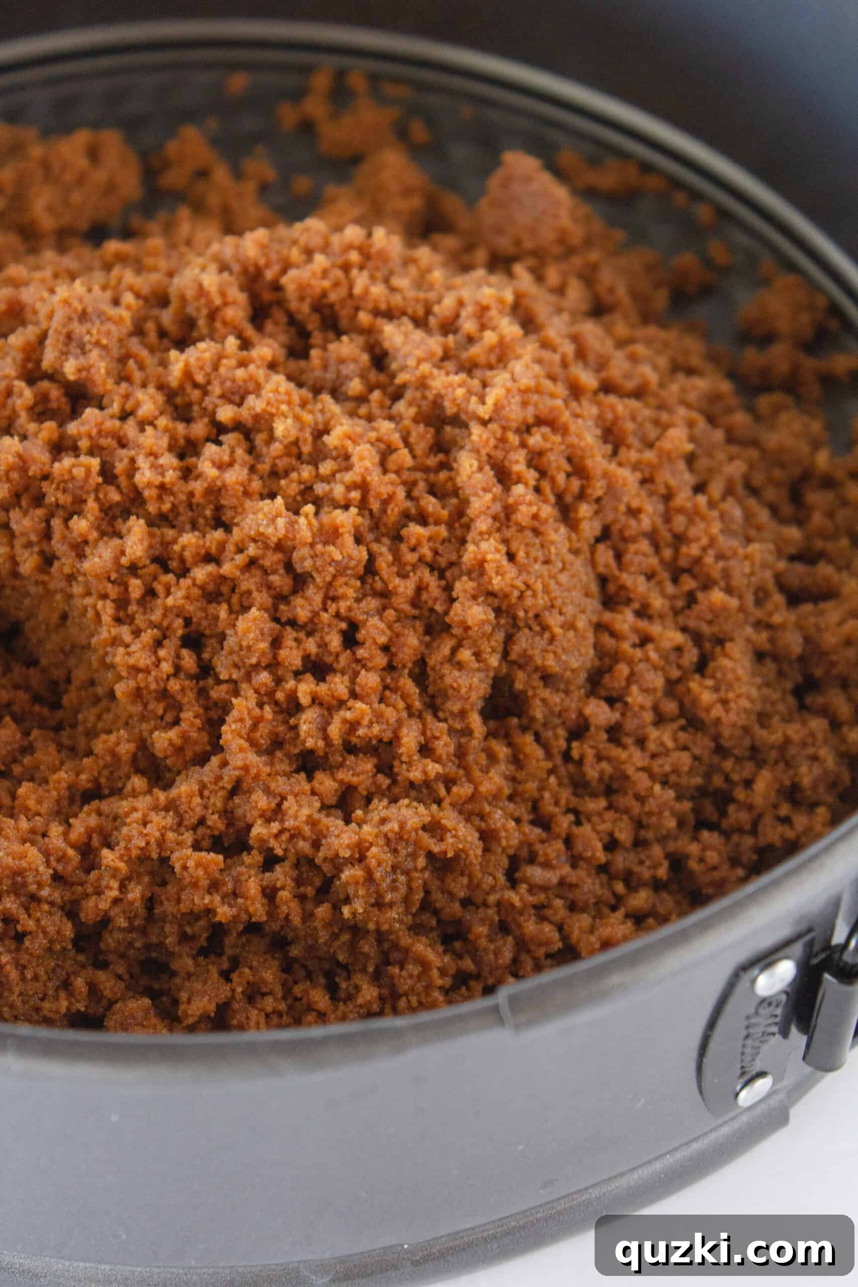 Decadent Cookie Butter No-Bake Cheesecake 5 Biscoff cookie crust being pressed into a springform pan
