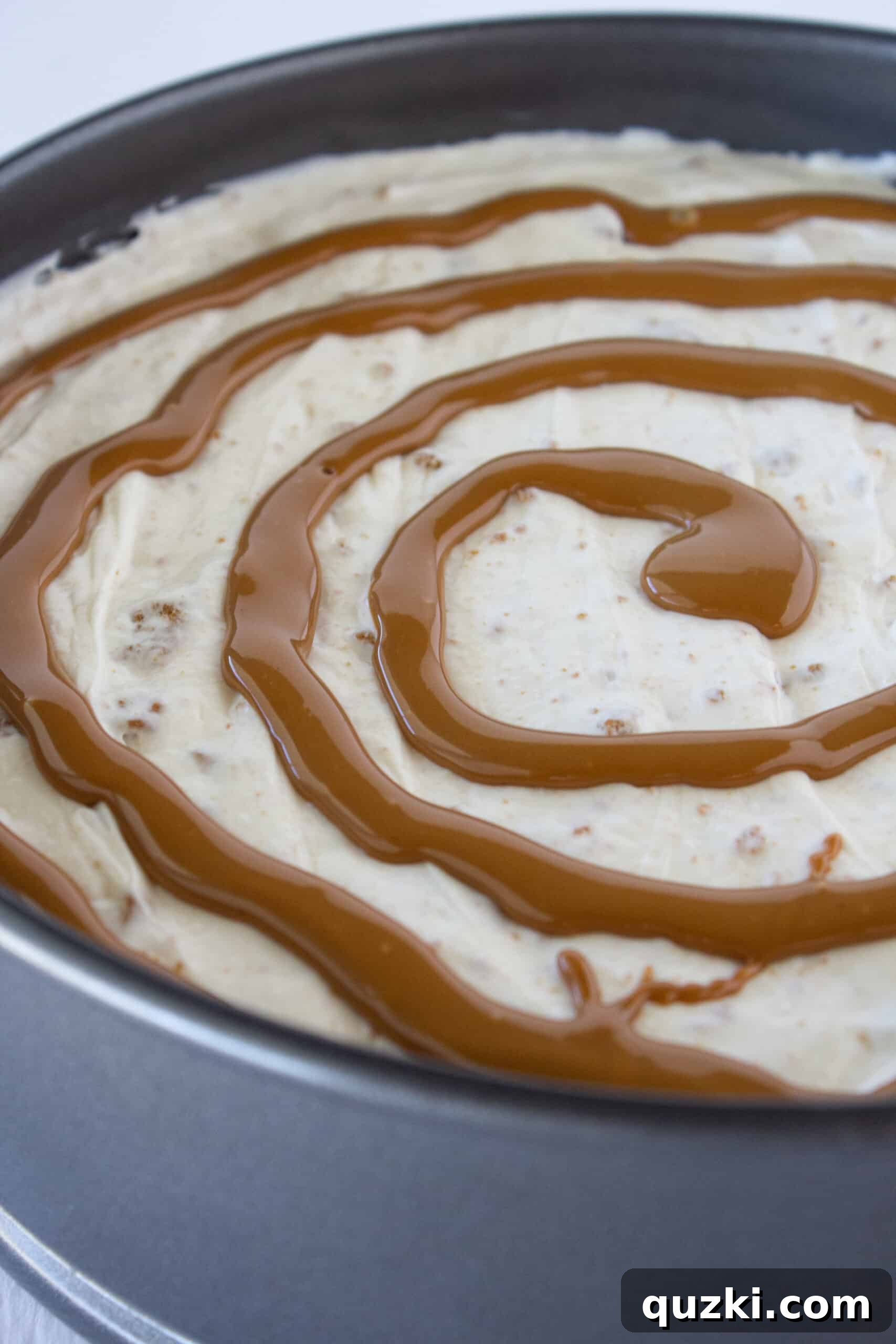 Decadent Cookie Butter No-Bake Cheesecake 10 Melted cookie butter being drizzled over the cheesecake filling in a circular pattern